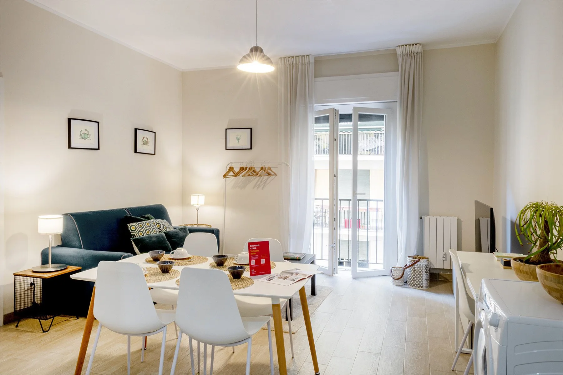 Comedor con mesa y sillas junto a una zona de estar y puertas acristaladas luminosas.