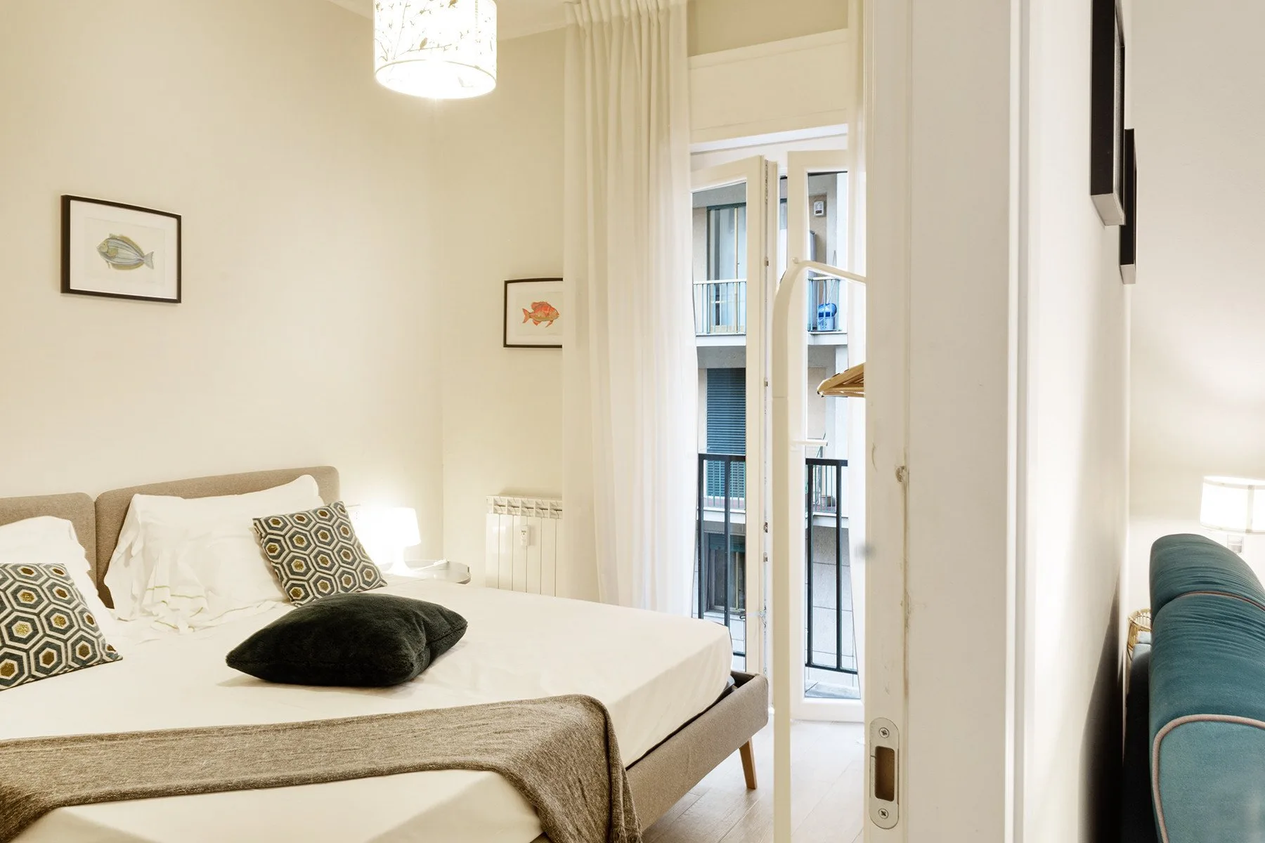 Un dormitorio luminoso con una cama junto a una alta puerta acristalada al balcón.