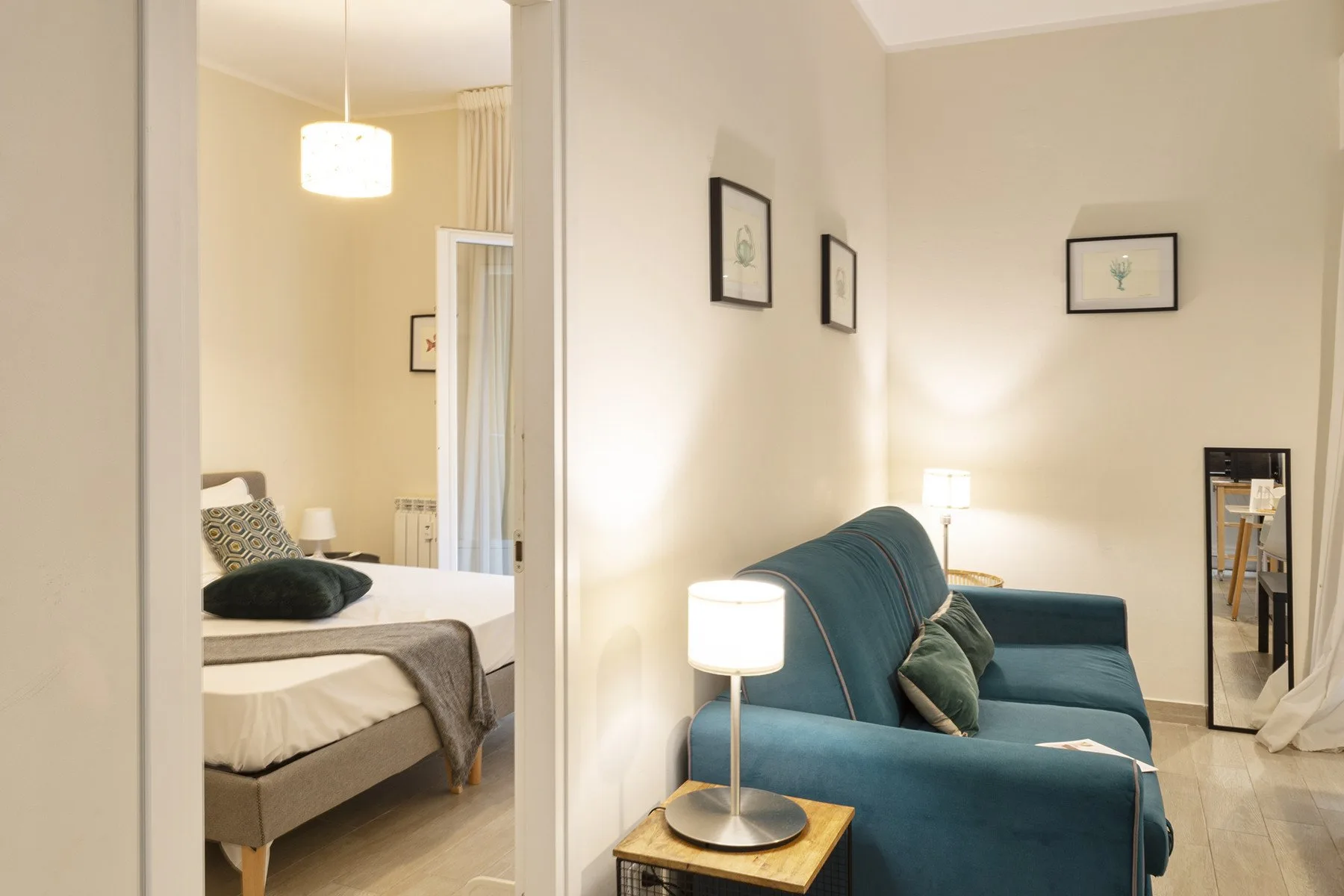 Una sala luminosa con asientos azules junto a un dormitorio abierto.