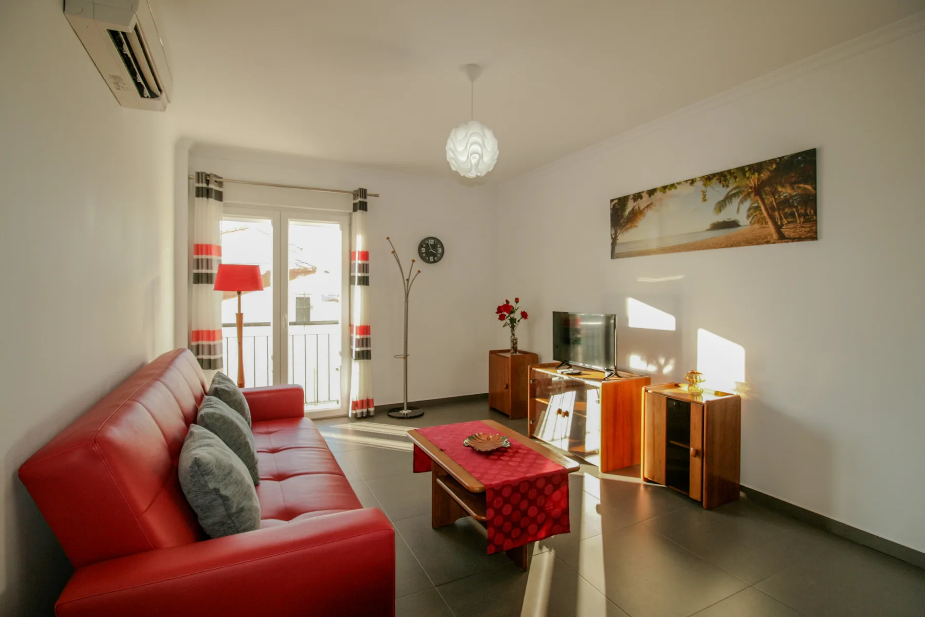 Una sala de estar con asientos rojos, una mesa de centro y un televisor.