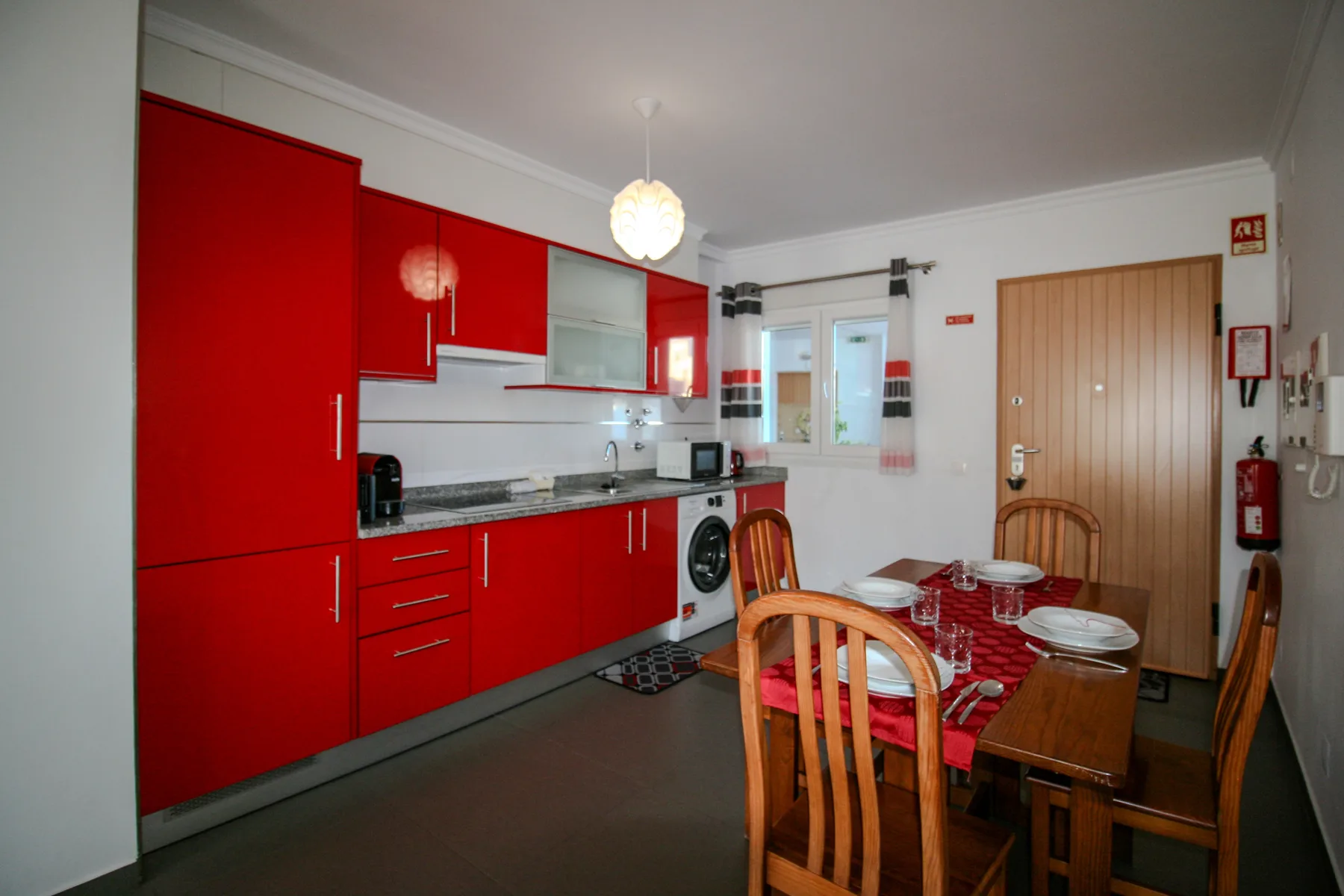 Una cocina y comedor con gabinetes rojos y una mesa de comedor de madera.