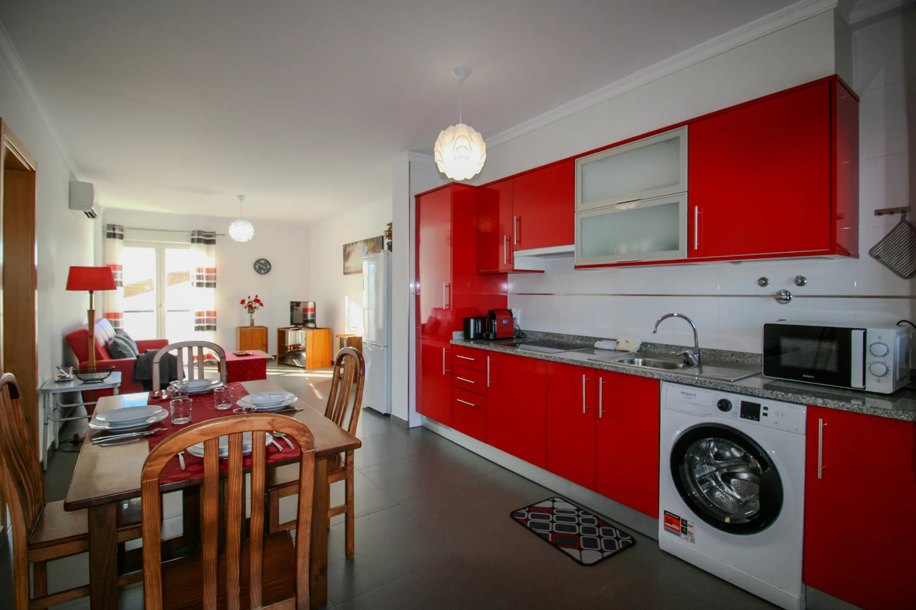 Una cocina y comedor de concepto abierto con armarios rojos y una mesa de madera.