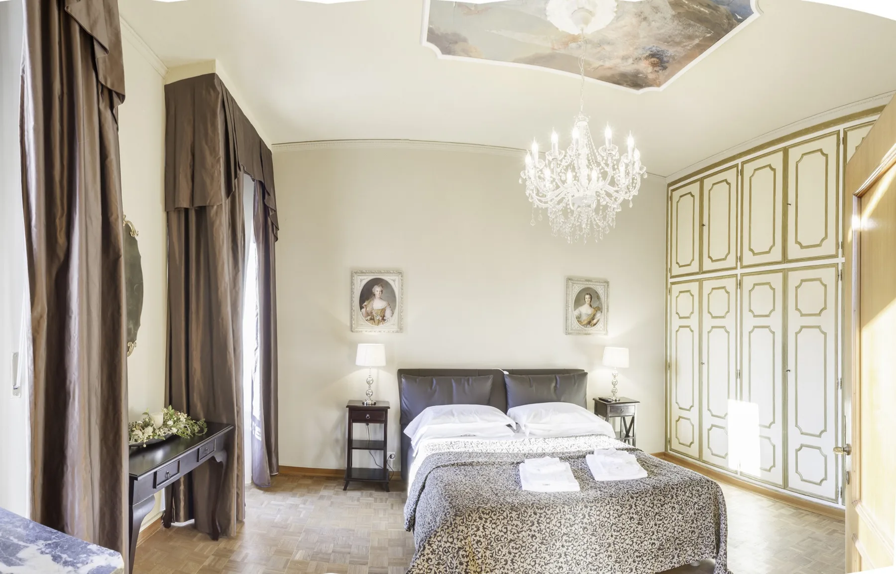 A bedroom with a neatly made bed and tall paneled wardrobes.