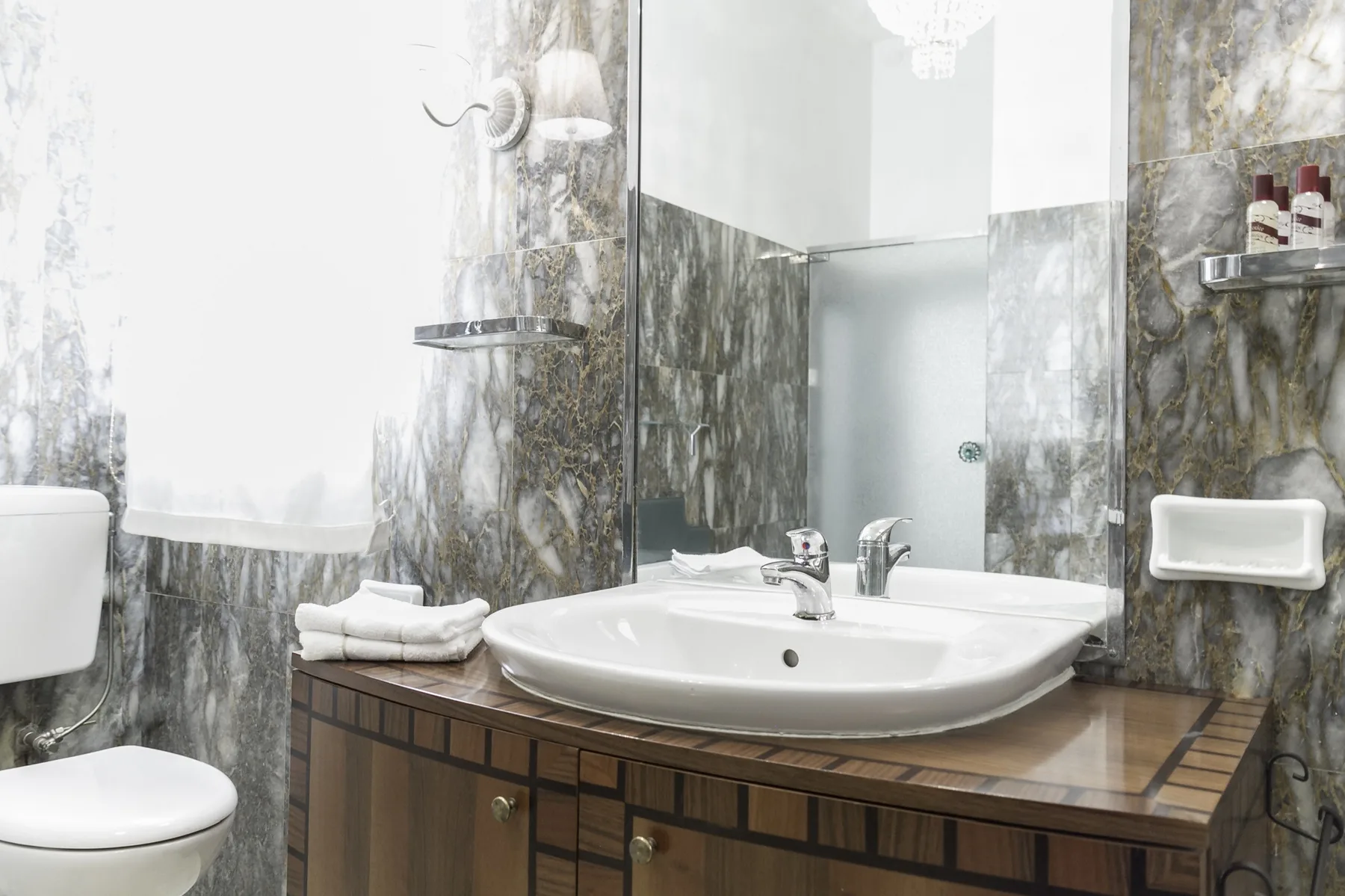 A bathroom vanity with a sink sits beside a toilet and tiled walls.