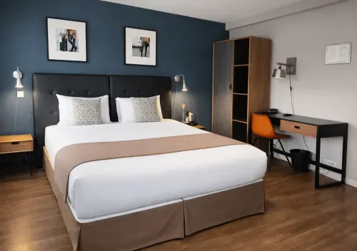Habitación moderna con cama tamaño queen, pared de acento azul oscuro, escritorio y suelo de madera.