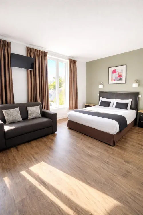 Habitación con vistas al jardín, cama tamaño queen, sofá y decoración contemporánea.