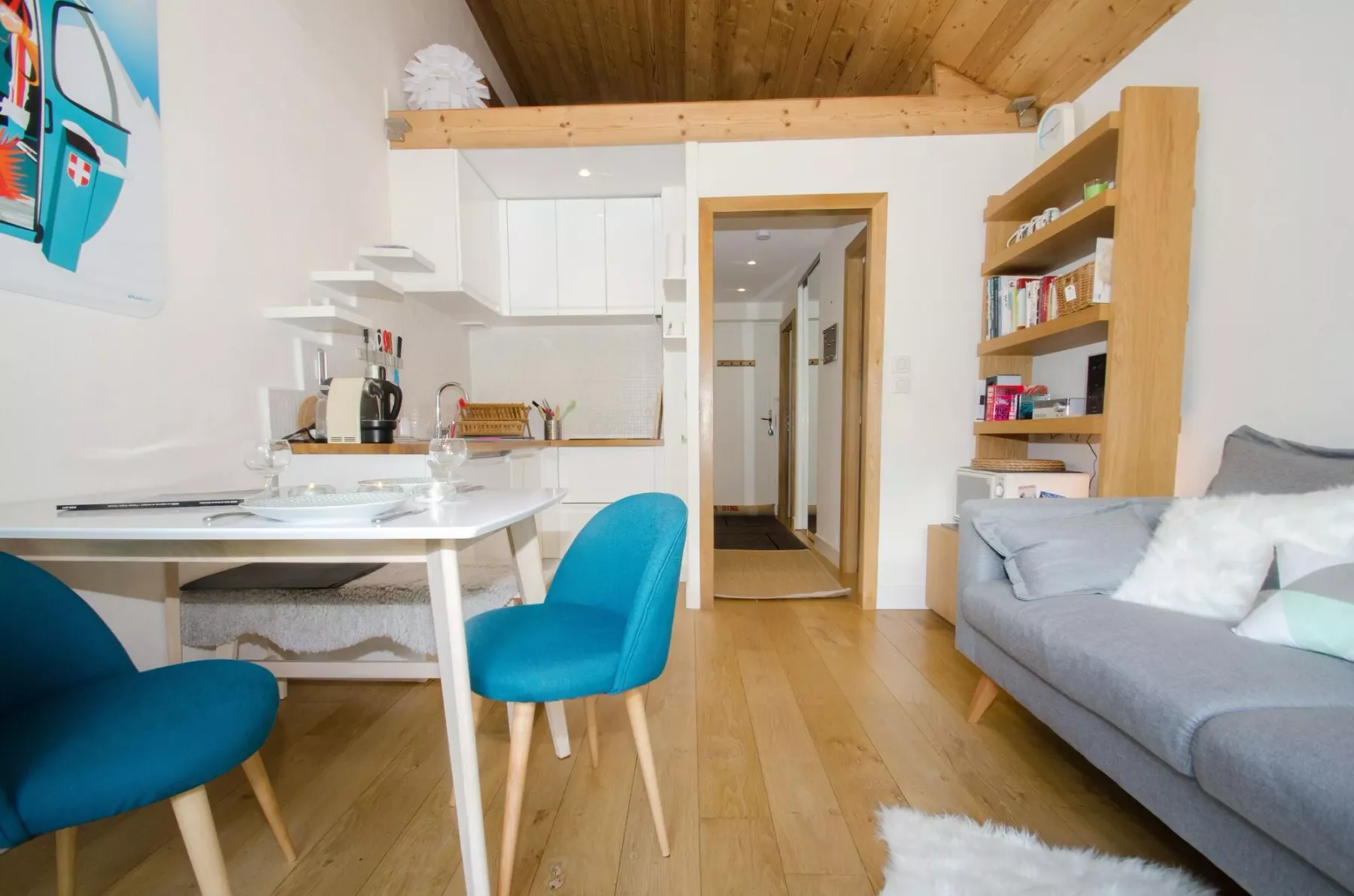 A compact living area combines a kitchenette, dining table, and seating.