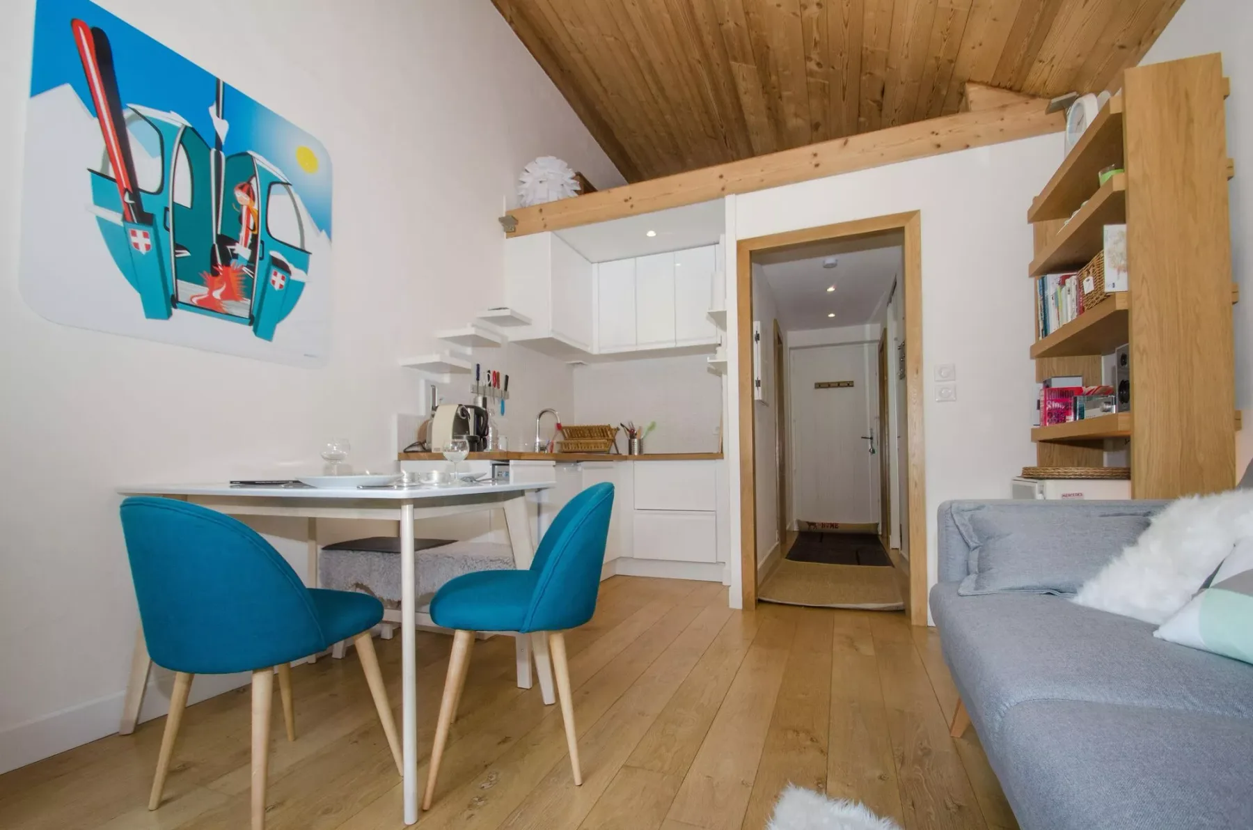 A compact living area with a dining table, blue seating, and a kitchenette.