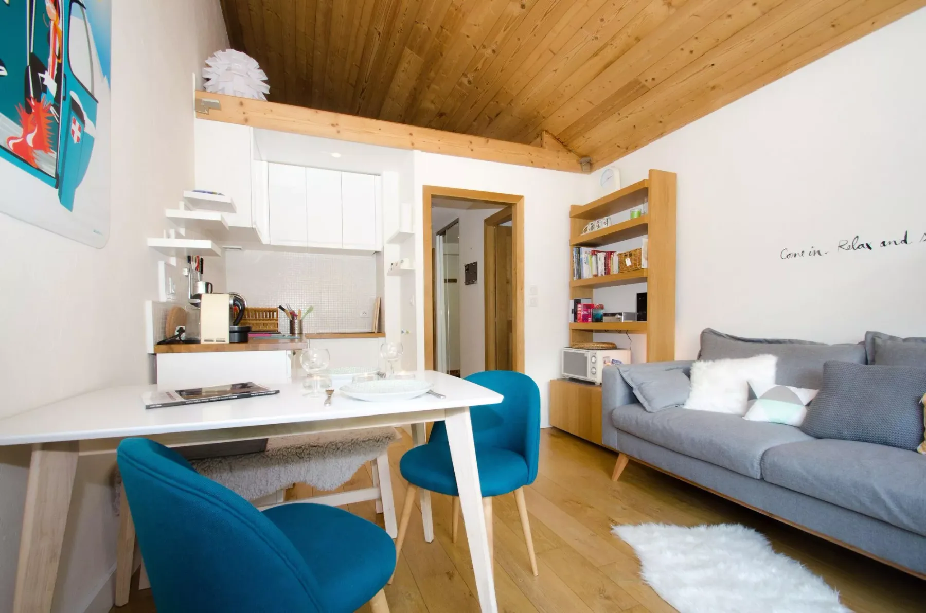 A bright living area with a table, blue seating, and a gray couch.