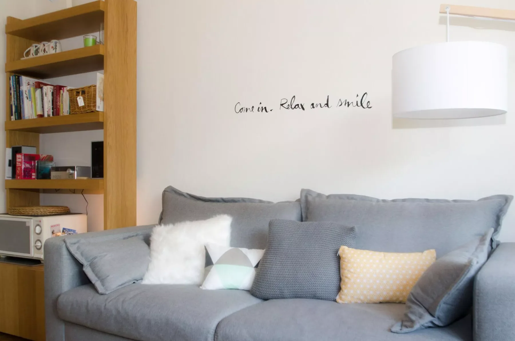 A living room with gray seating and a wall-mounted light.