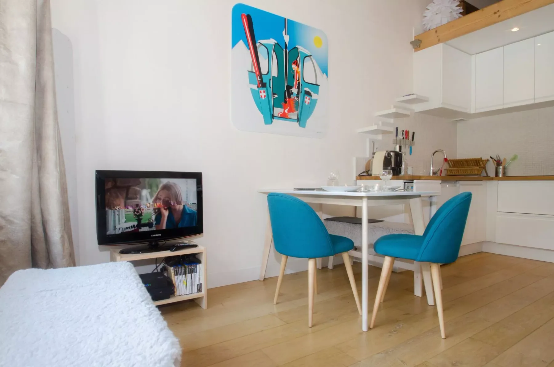 A compact living and dining area with turquoise seating and a small television.