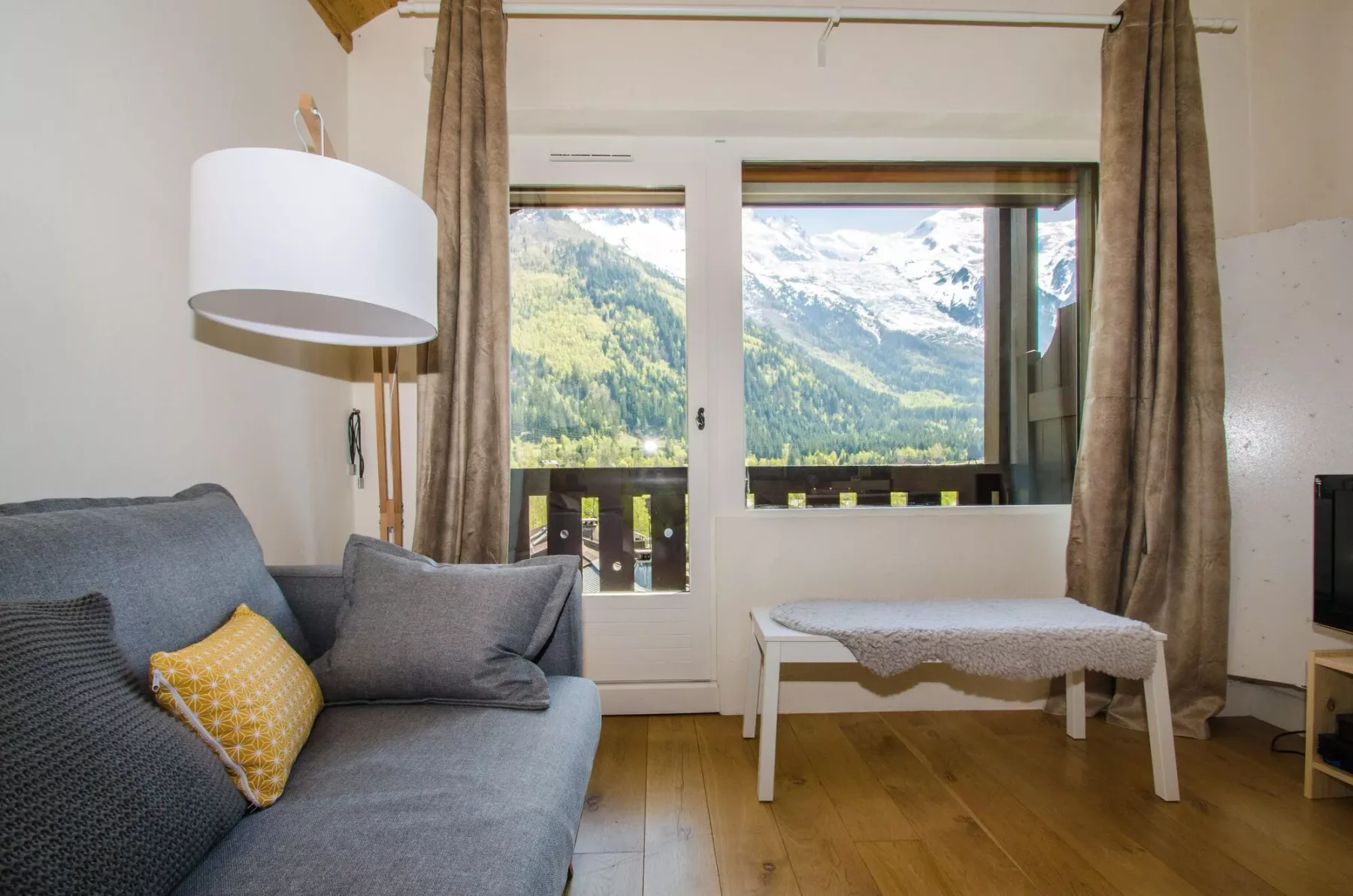 A living room with seating beside large windows overlooking a mountain landscape.