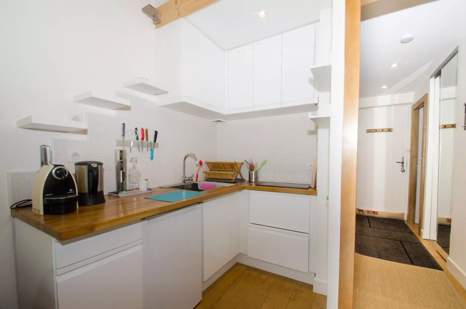 A compact kitchen with white cabinets and a wooden countertop.