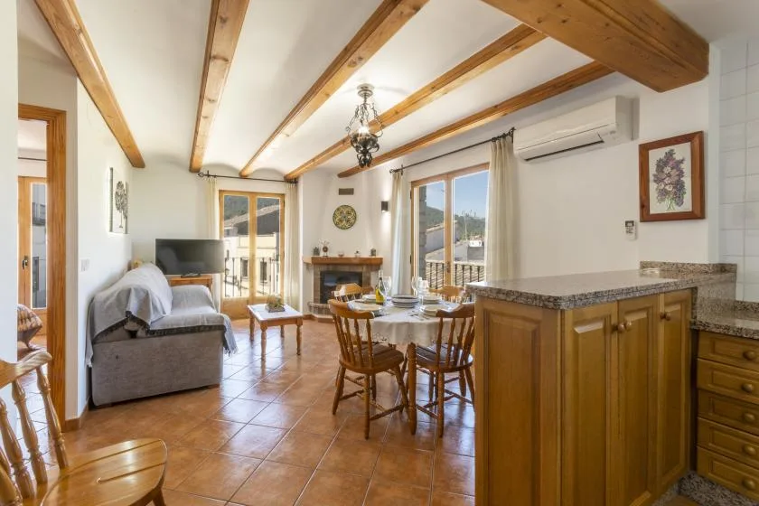 A bright living and dining area with wooden ceiling beams and a kitchen counter.