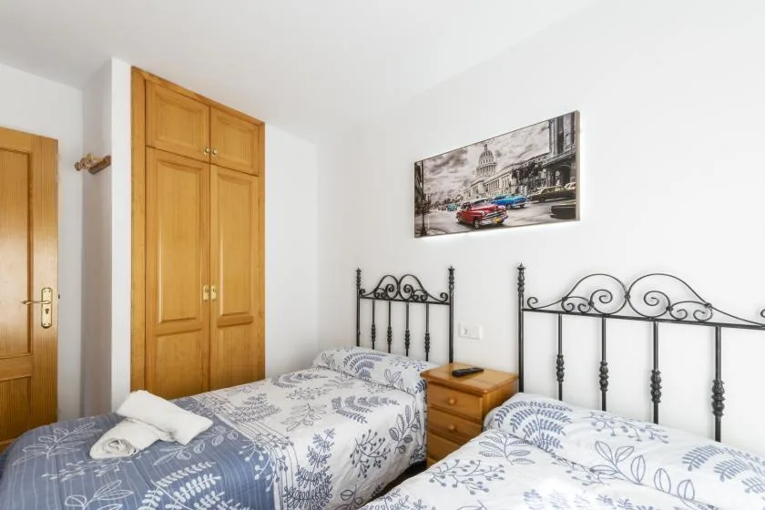 A bedroom with two beds, wooden wardrobes, and framed artwork.