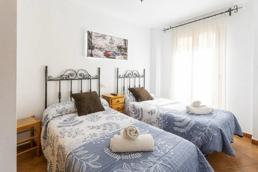 A bright bedroom with two beds dressed in blue patterned bedding.
