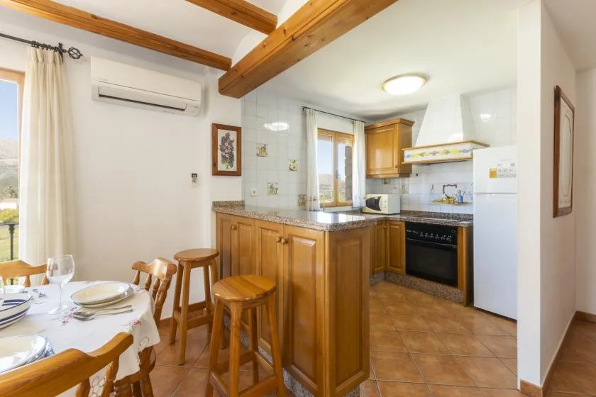 A bright kitchen with wooden cabinets and a dining table beside the window.
