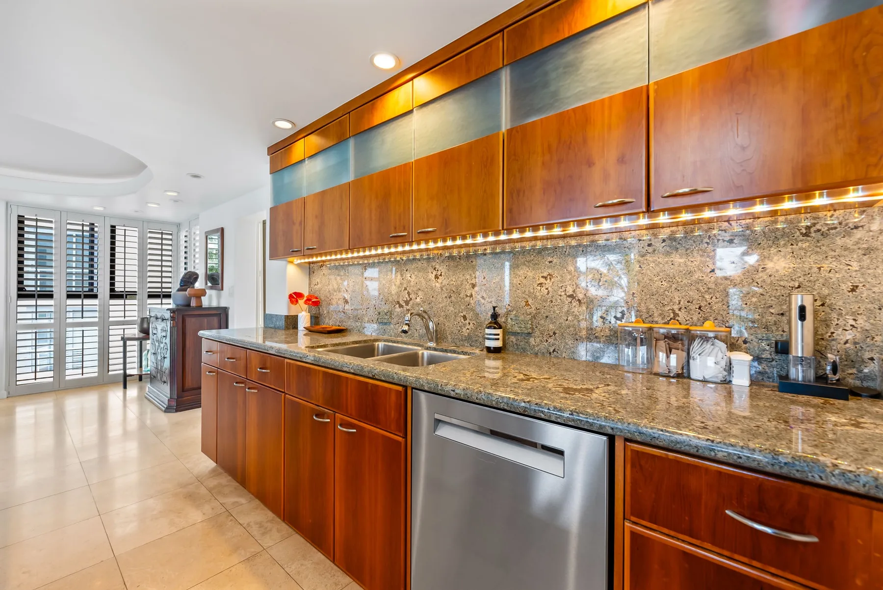 Una cocina moderna con armarios de madera y una encimera larga de piedra.