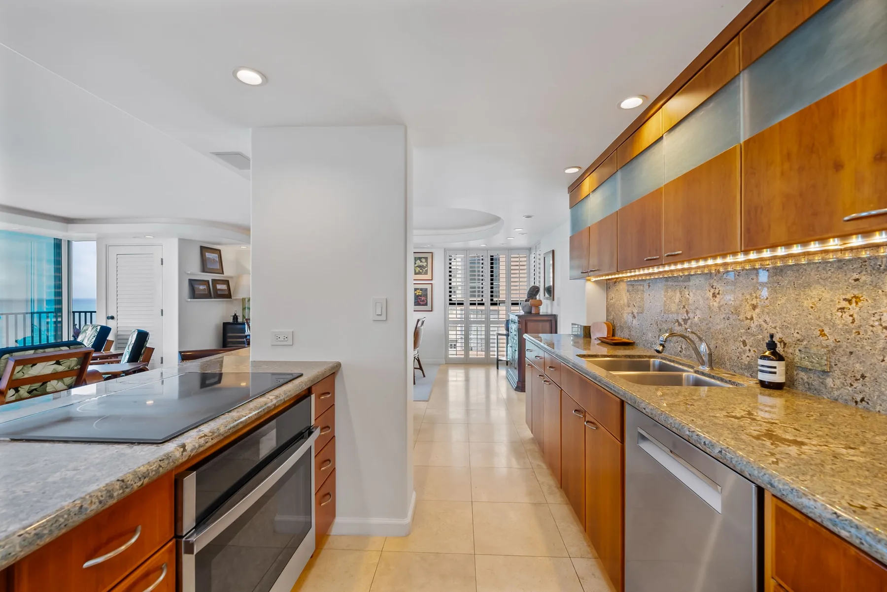 Una cocina luminosa con gabinetes de madera, encimeras de piedra y electrodomésticos de acero inoxidable.