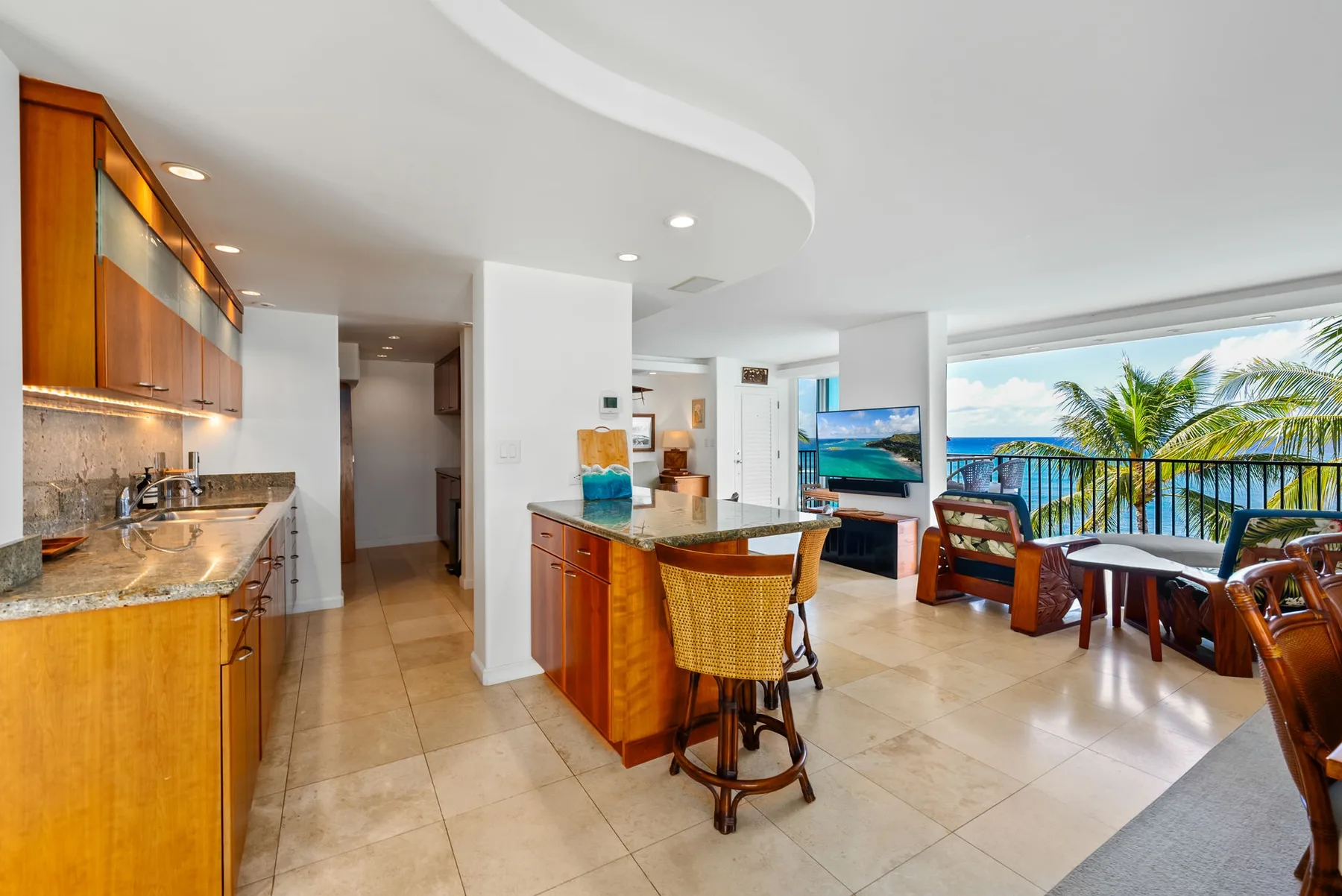 Una cocina y comedor de planta abierta, con una barra y asientos junto a grandes ventanas.