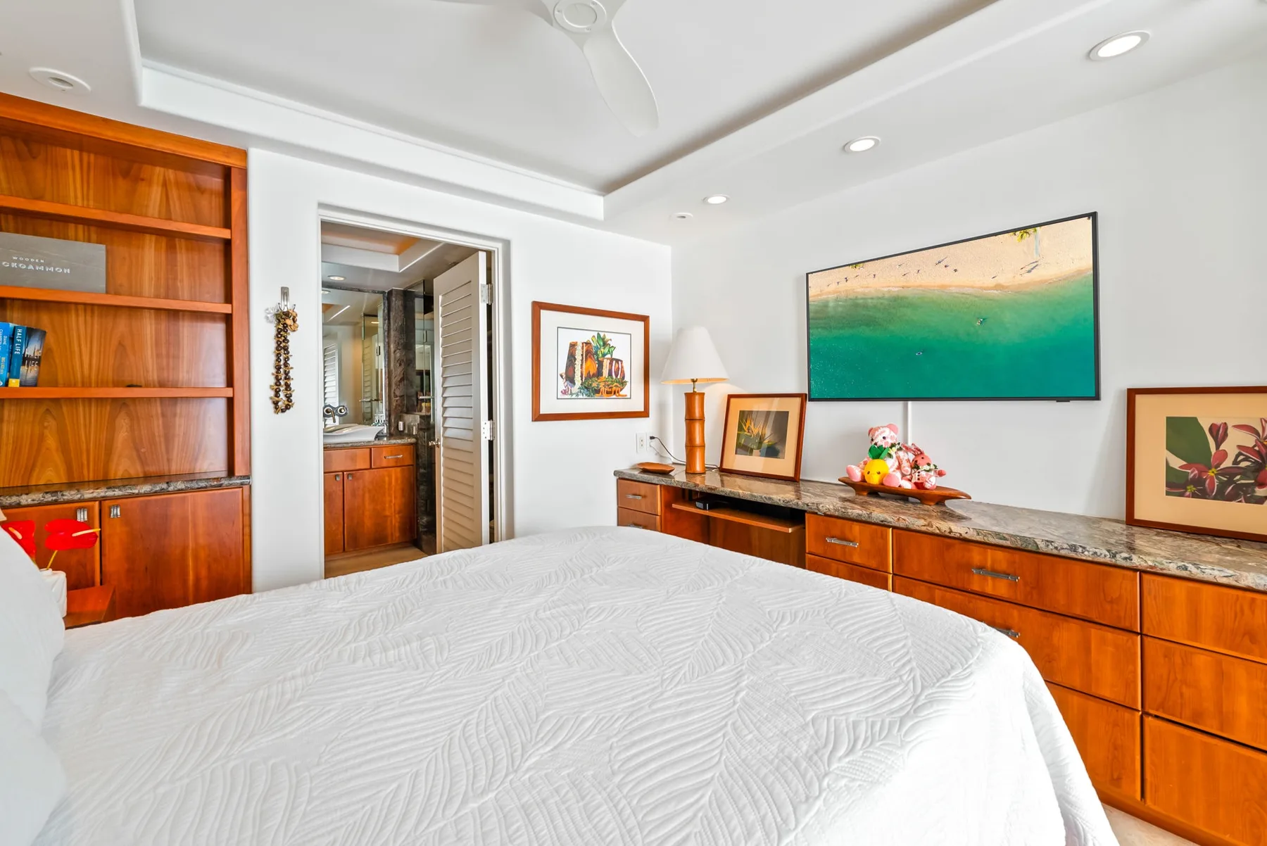 Un dormitorio con una cama cubierta de blanco y muebles de madera.
