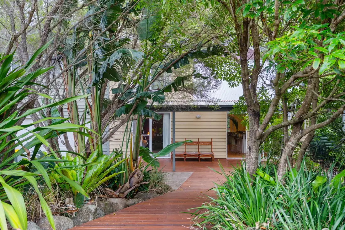 Un sendero de jardín atraviesa la vegetación hasta una casa con un pequeño porche.