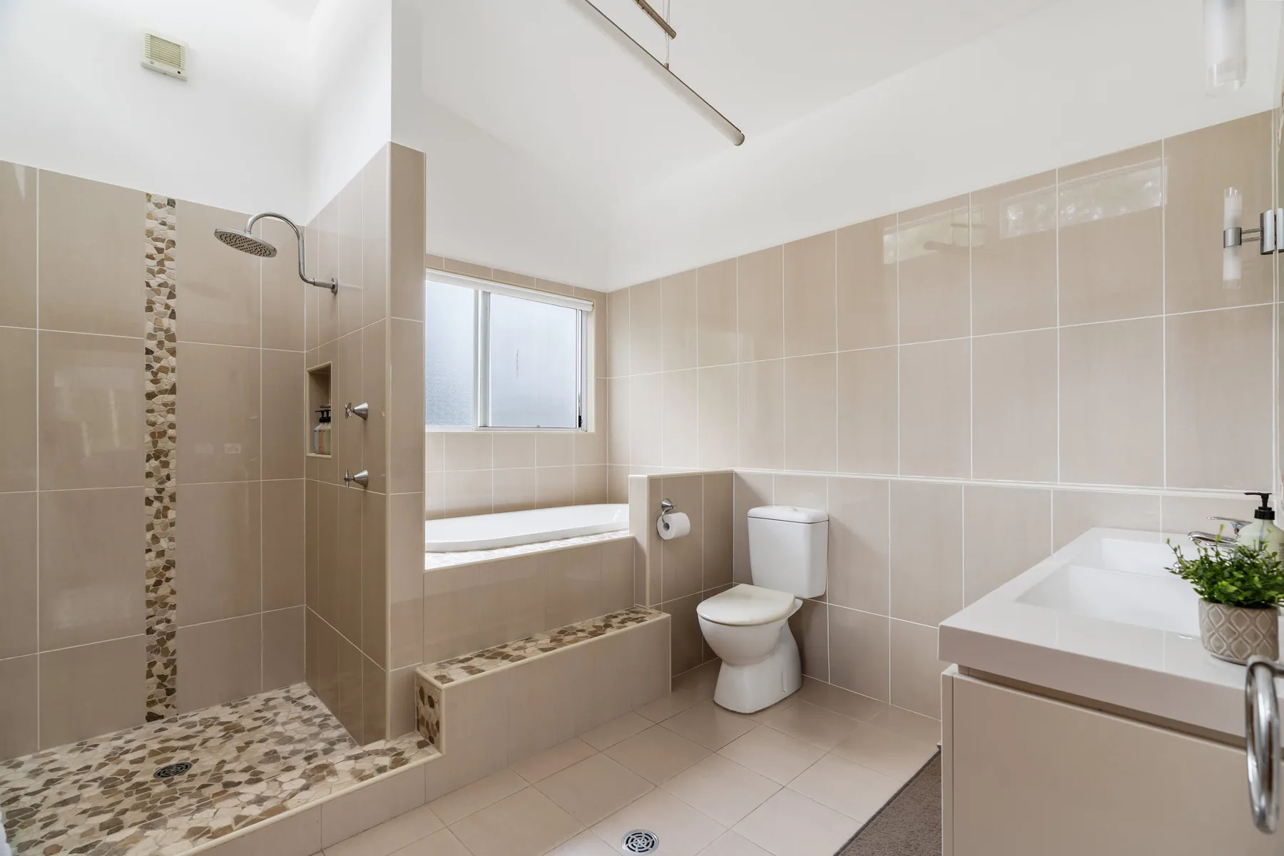 Un baño alicatado con ducha, bañera, inodoro y lavabo.