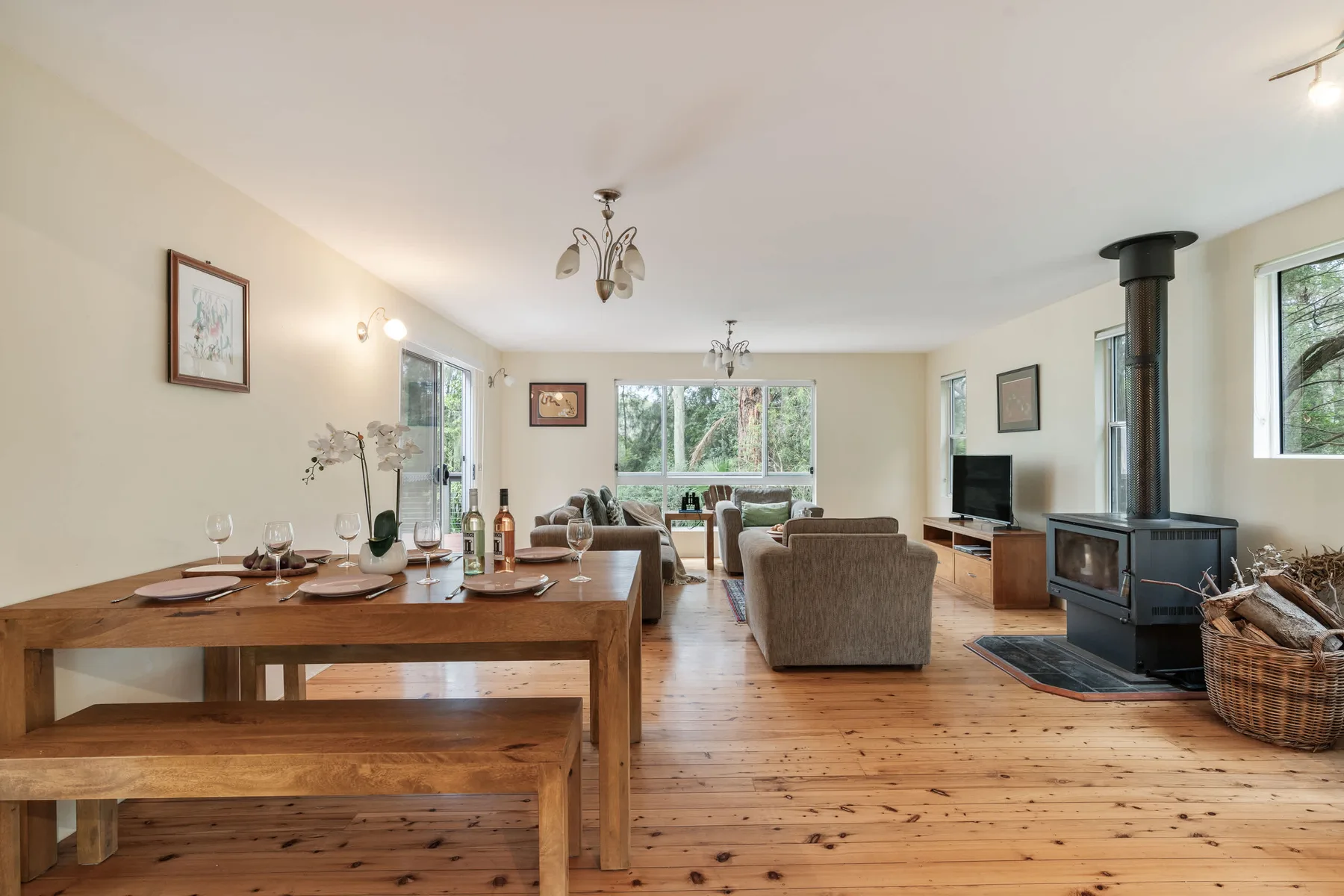 Una sala-comedor diáfana y luminosa, con una estufa de leña y ventanas grandes.