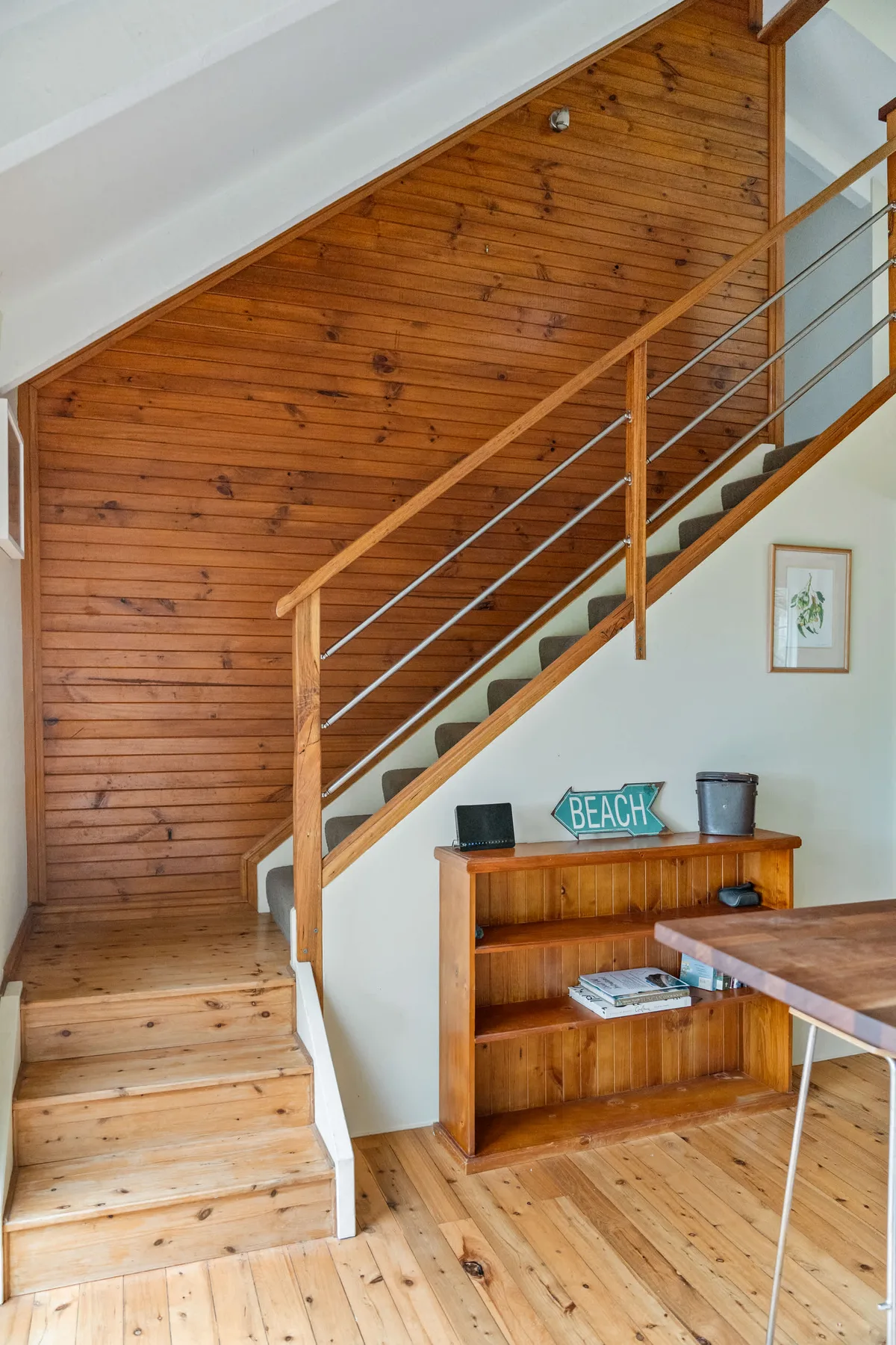 Una escalera de madera sube junto a una estantería en el interior.