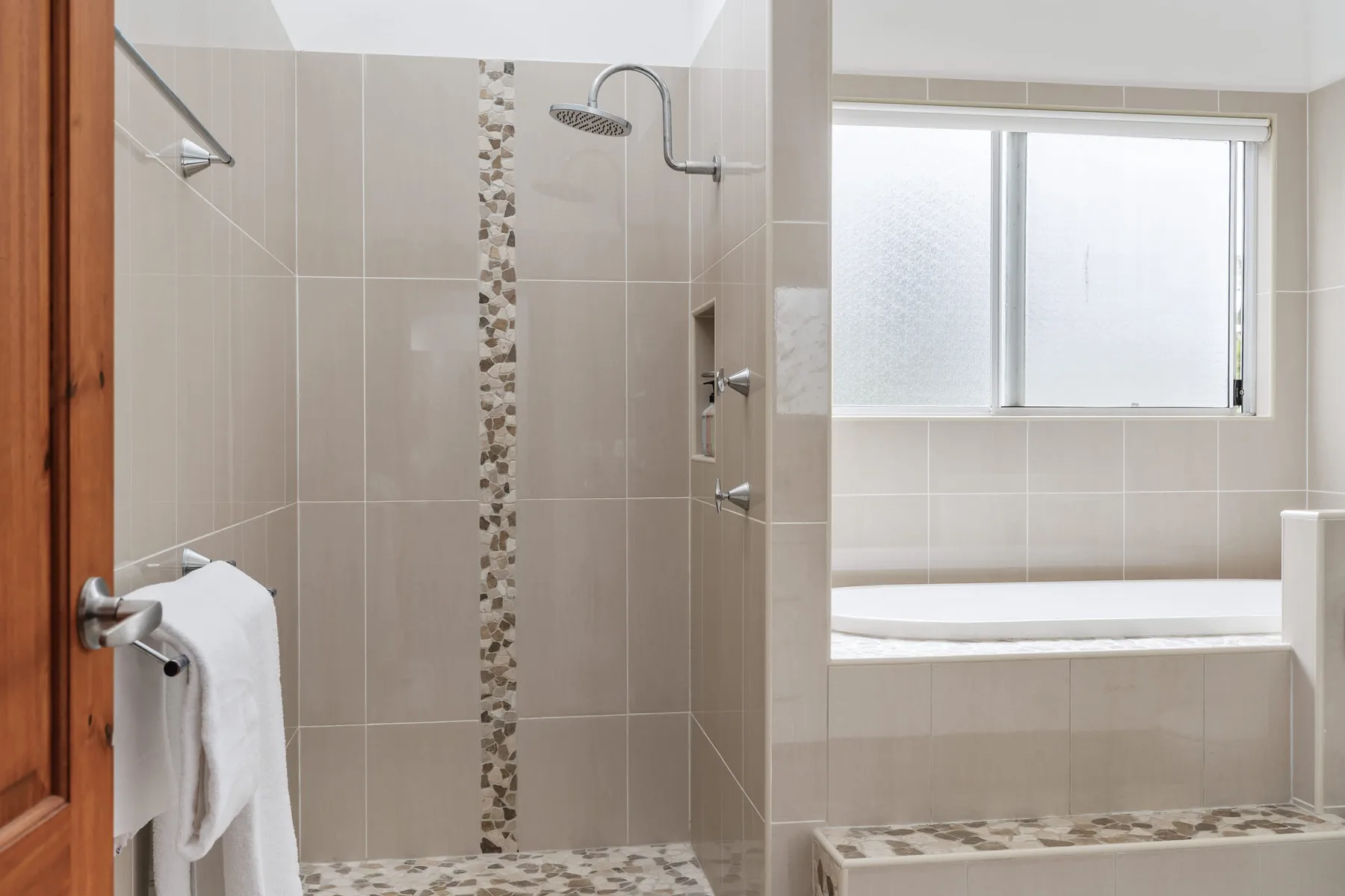 Un baño con azulejos, una ducha y una bañera.
