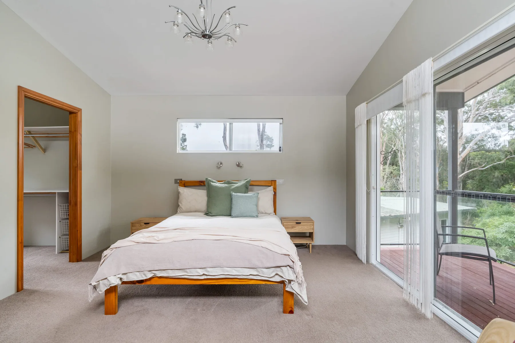 Un dormitorio con una cama, mesitas de noche y puertas de vidrio que dan a una terraza.