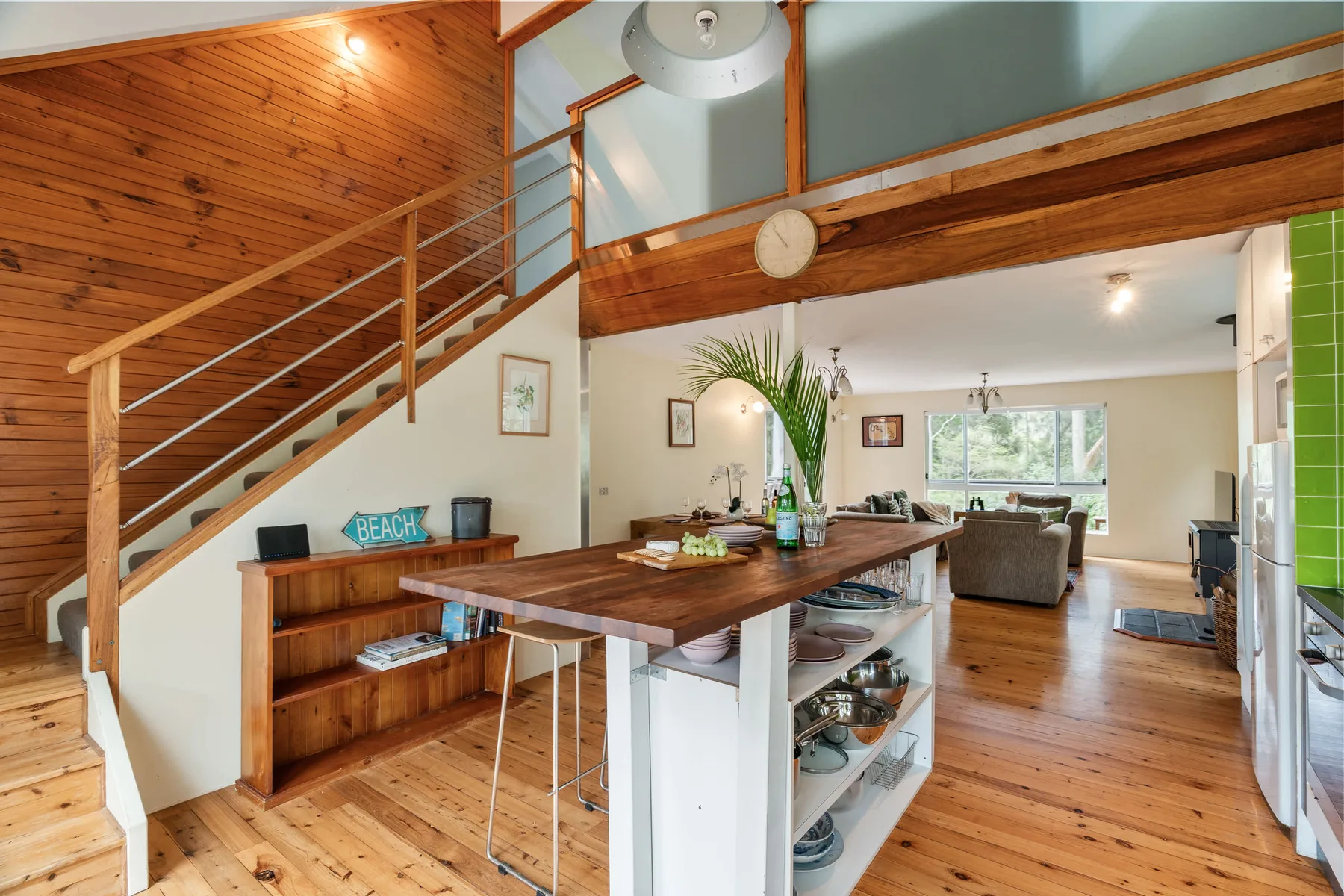Una cocina y comedor de espacio abierto con una barra de madera y una escalera.