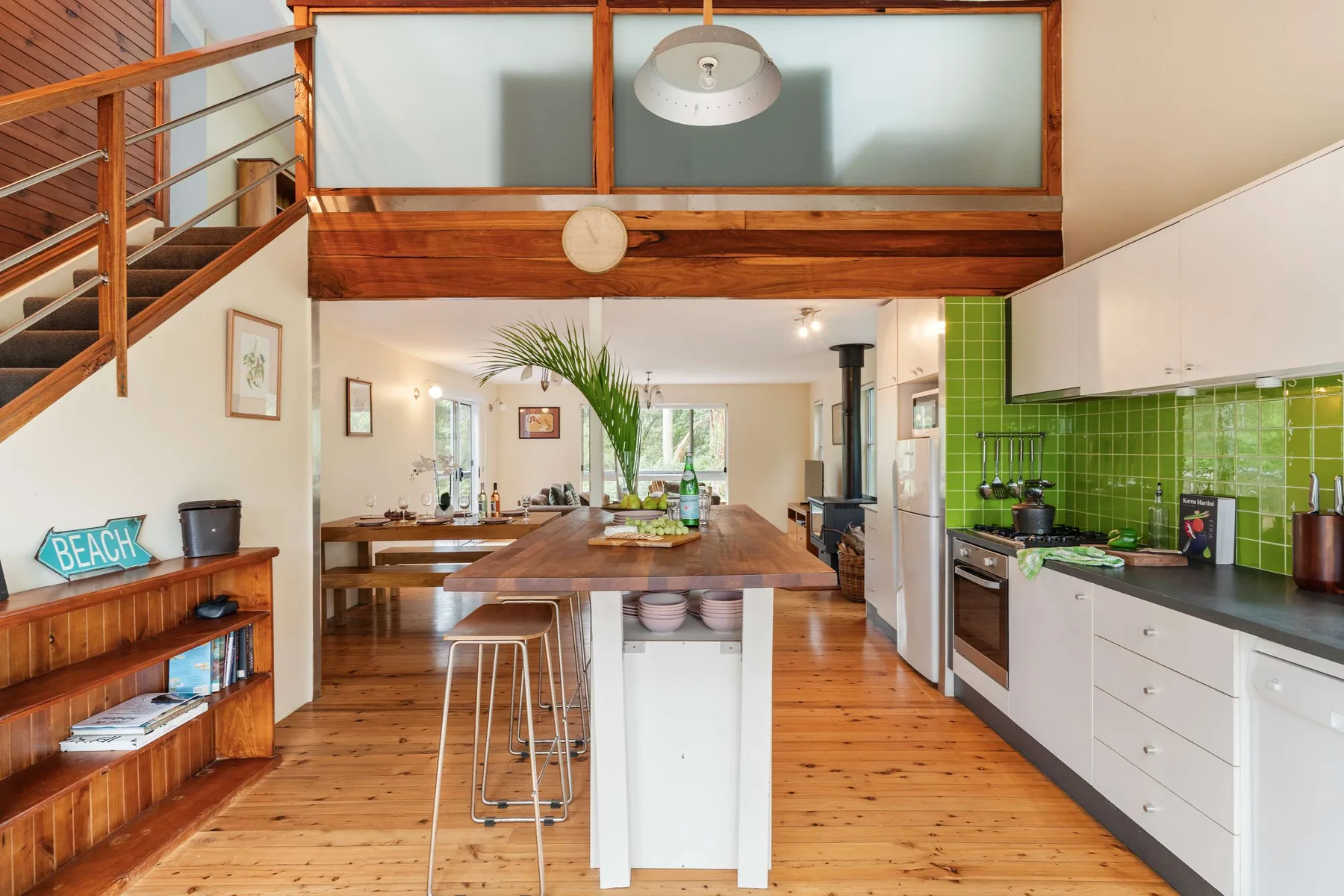 Cocina y comedor de planta abierta, con una isla larga y azulejos verdes.