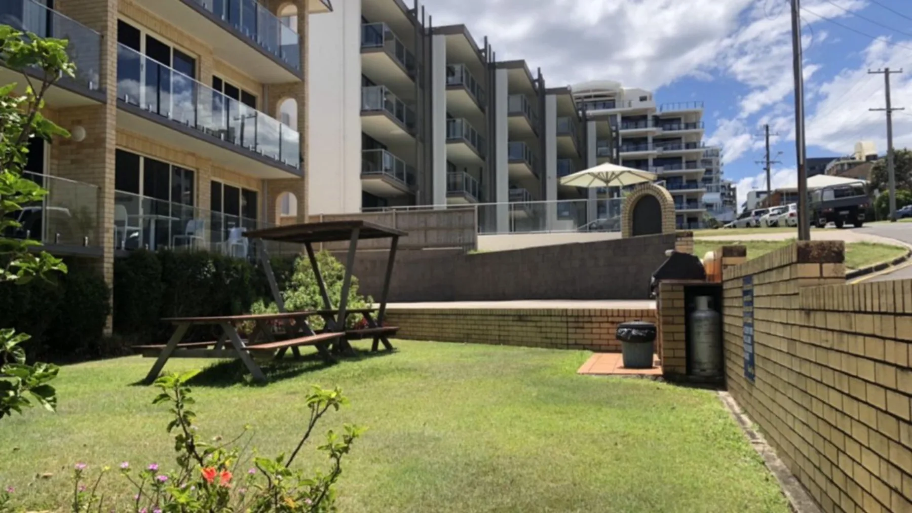 A landscaped courtyard with picnic seating sits beside multi-story buildings.