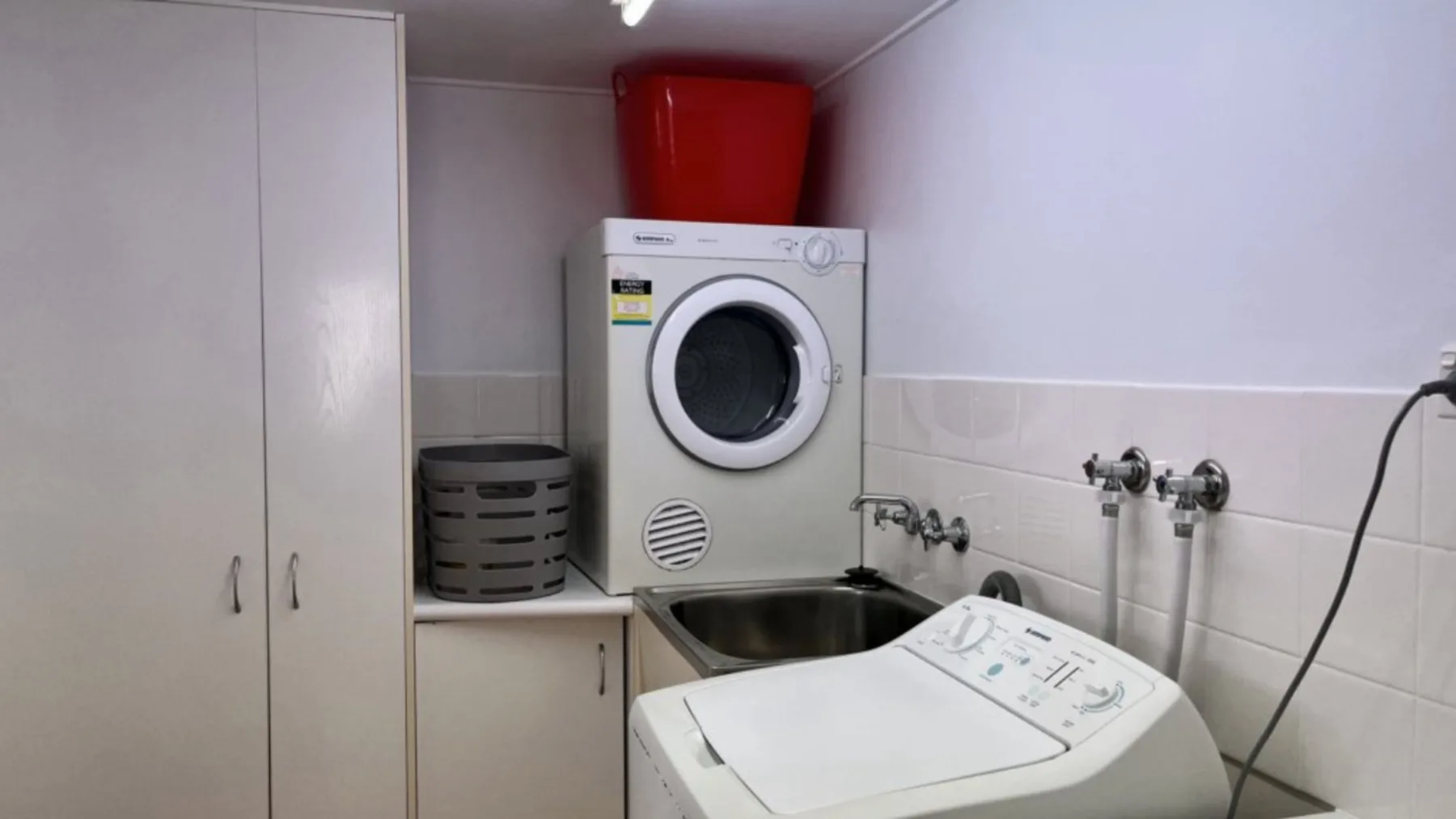 A laundry room with a front-loading washing machine and a top-loading washing machine.