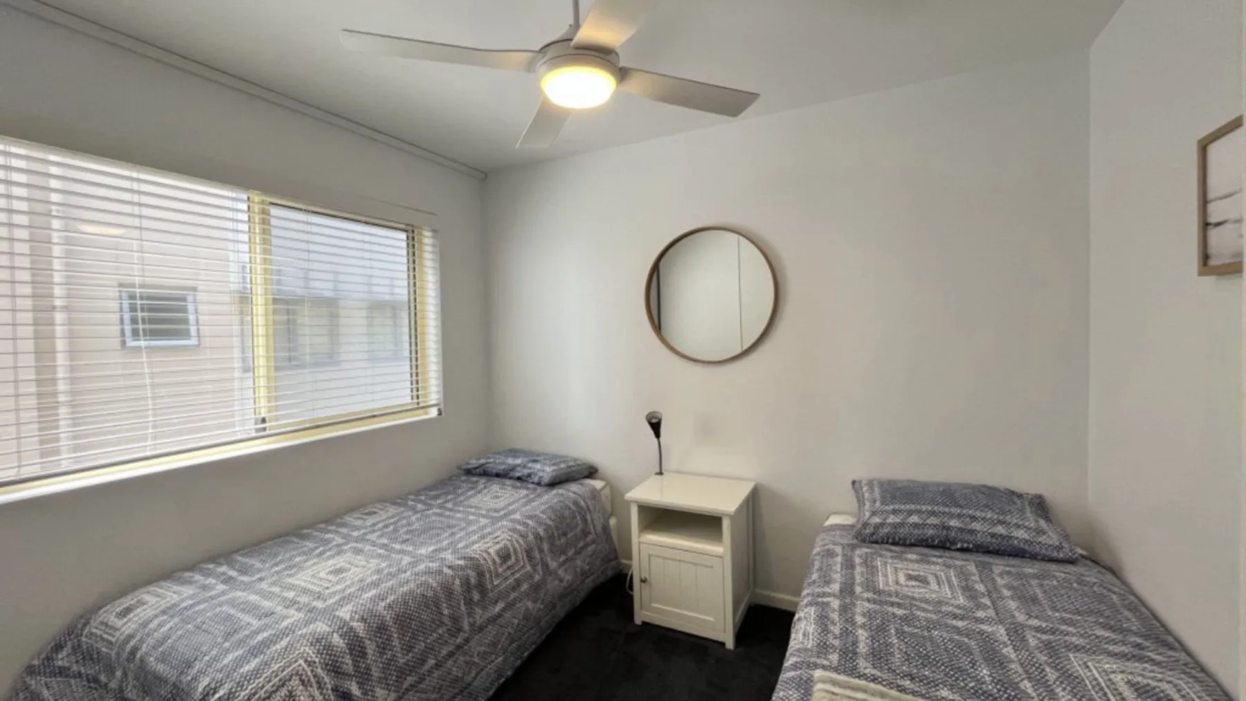 A bedroom with two single beds and a bedside table.