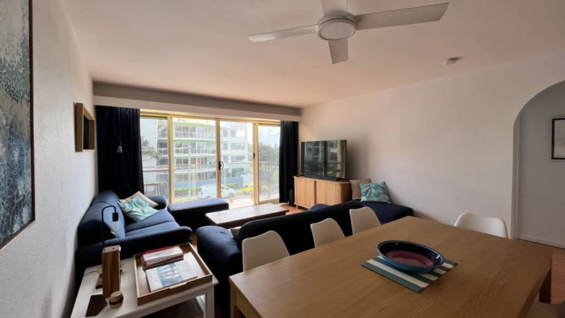 A living and dining area with seating, a dining table, and windows.