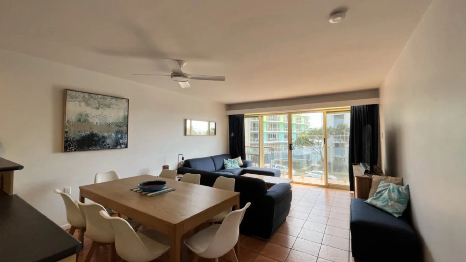 A living room with seating around a dining table and sliding glass doors.
