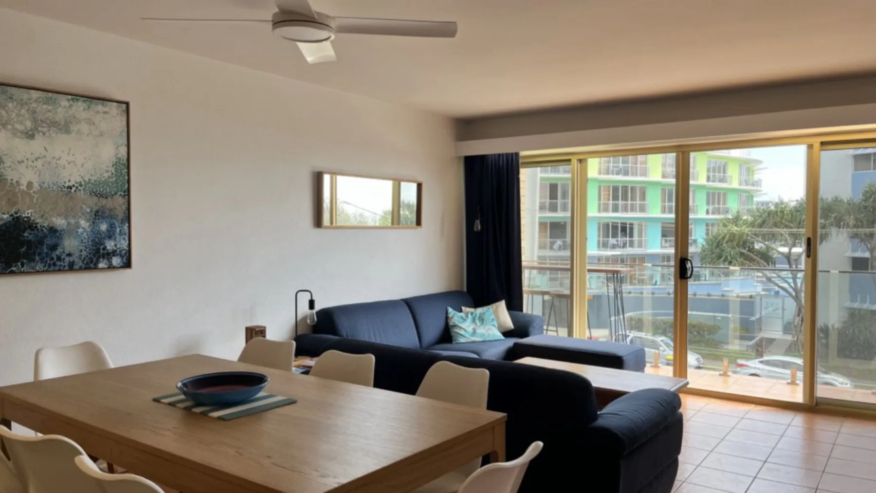 A living and dining area with seating beside glass doors opening onto a balcony.