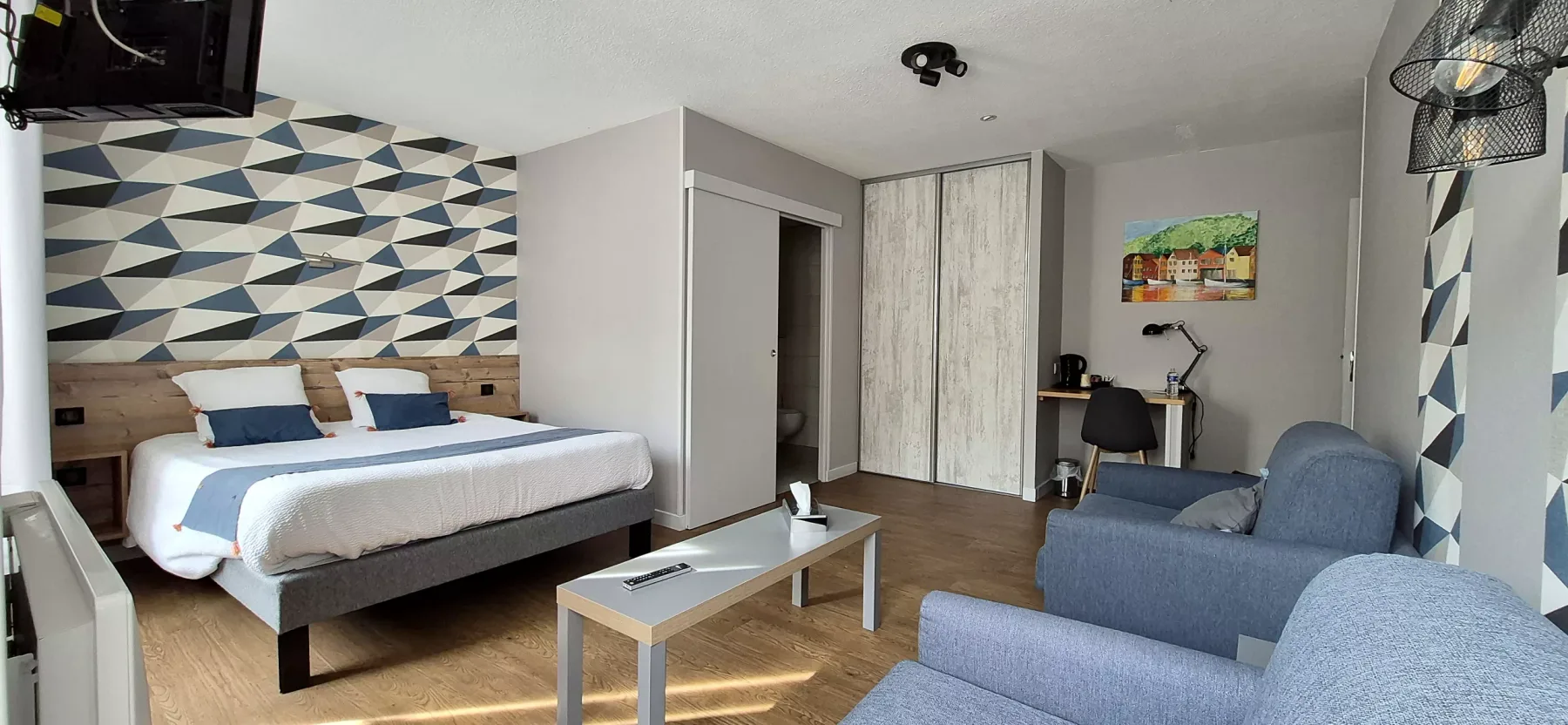 Dormitorio azul con cama doble, asientos y escritorio