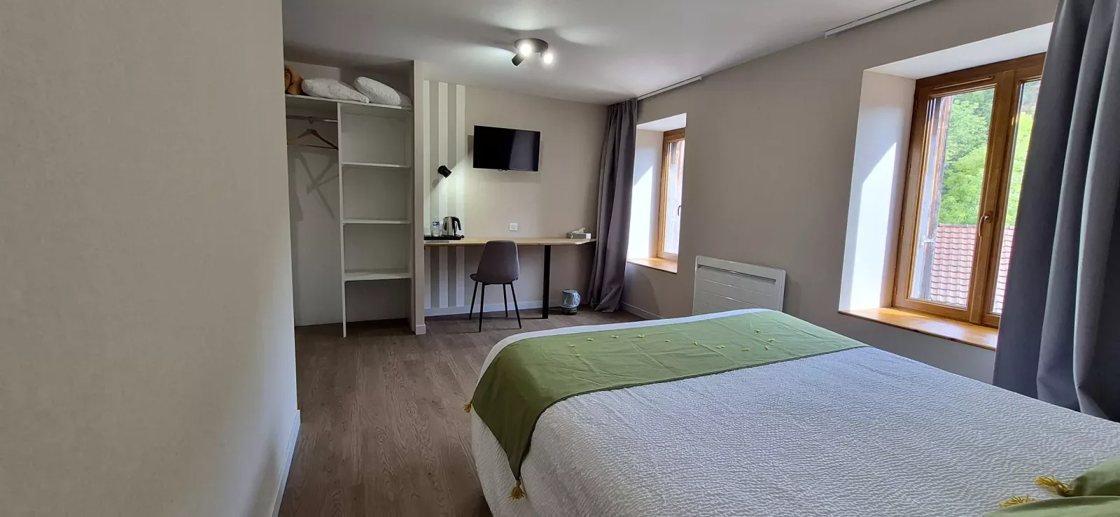 Dormitorio en tonos verdes con escritorio y ventanas con vistas al pueblo