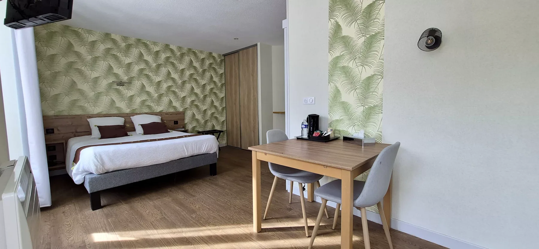 Dormitorio con papel pintado con motivos de hojas y cama doble