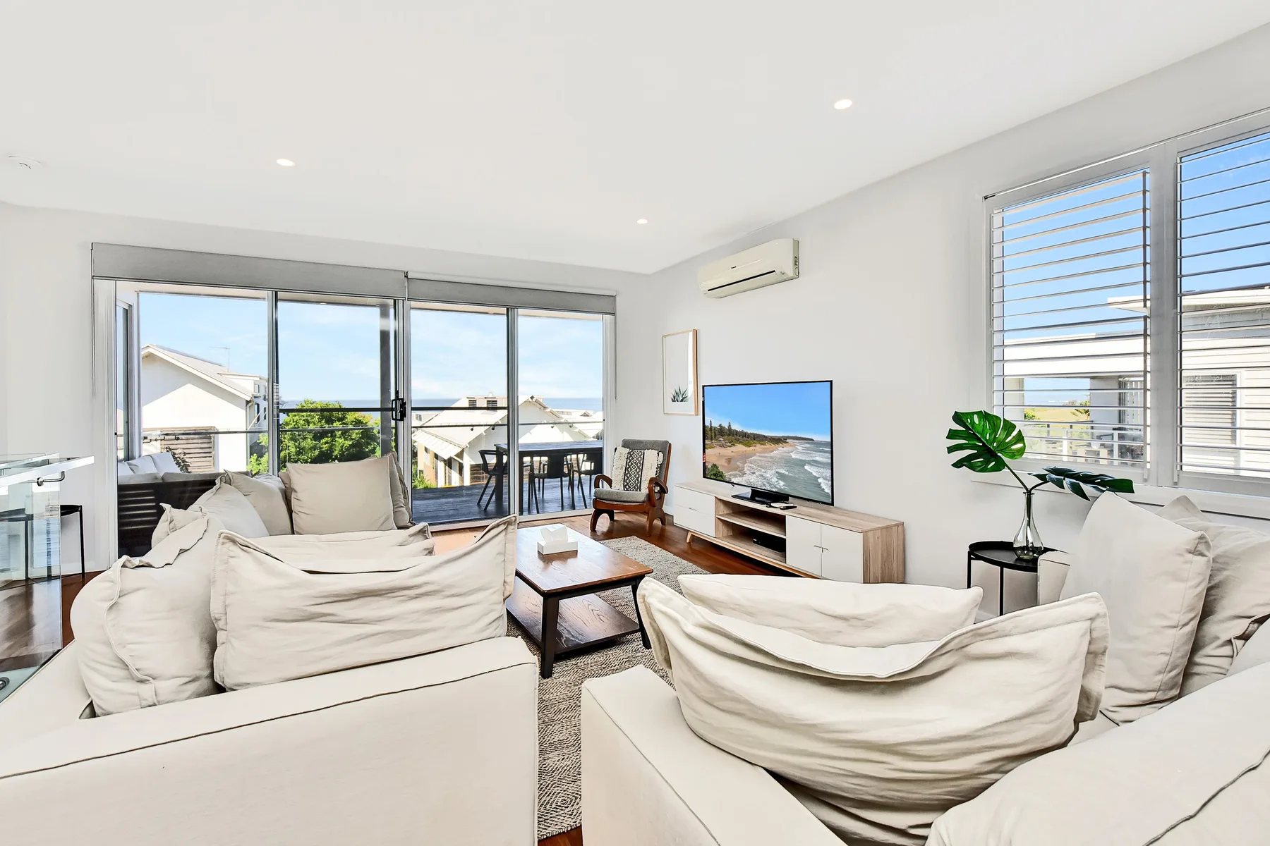 A bright living room with seating arranged around a coffee table and television.