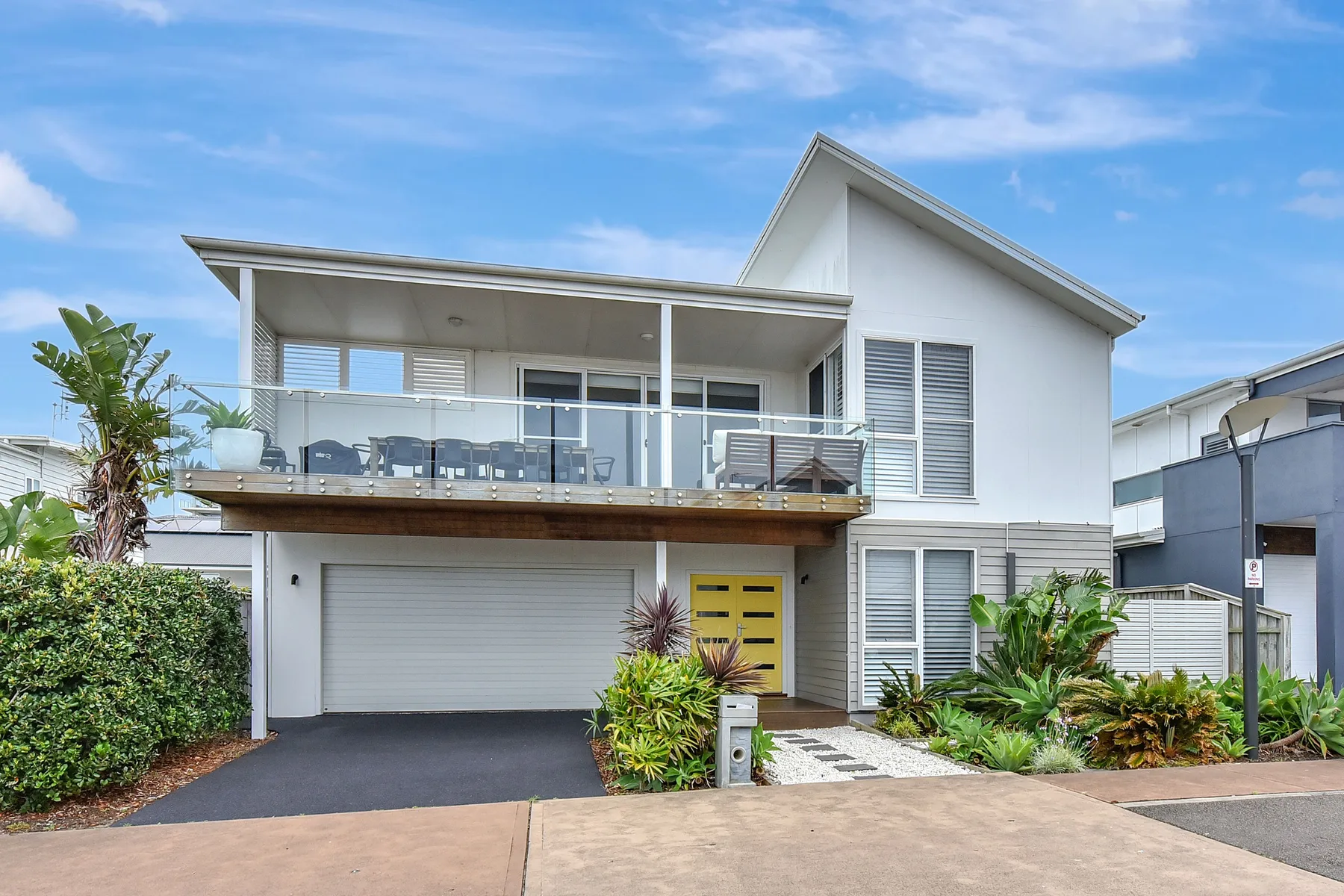 A modern white house with a glass-railed balcony and garage.