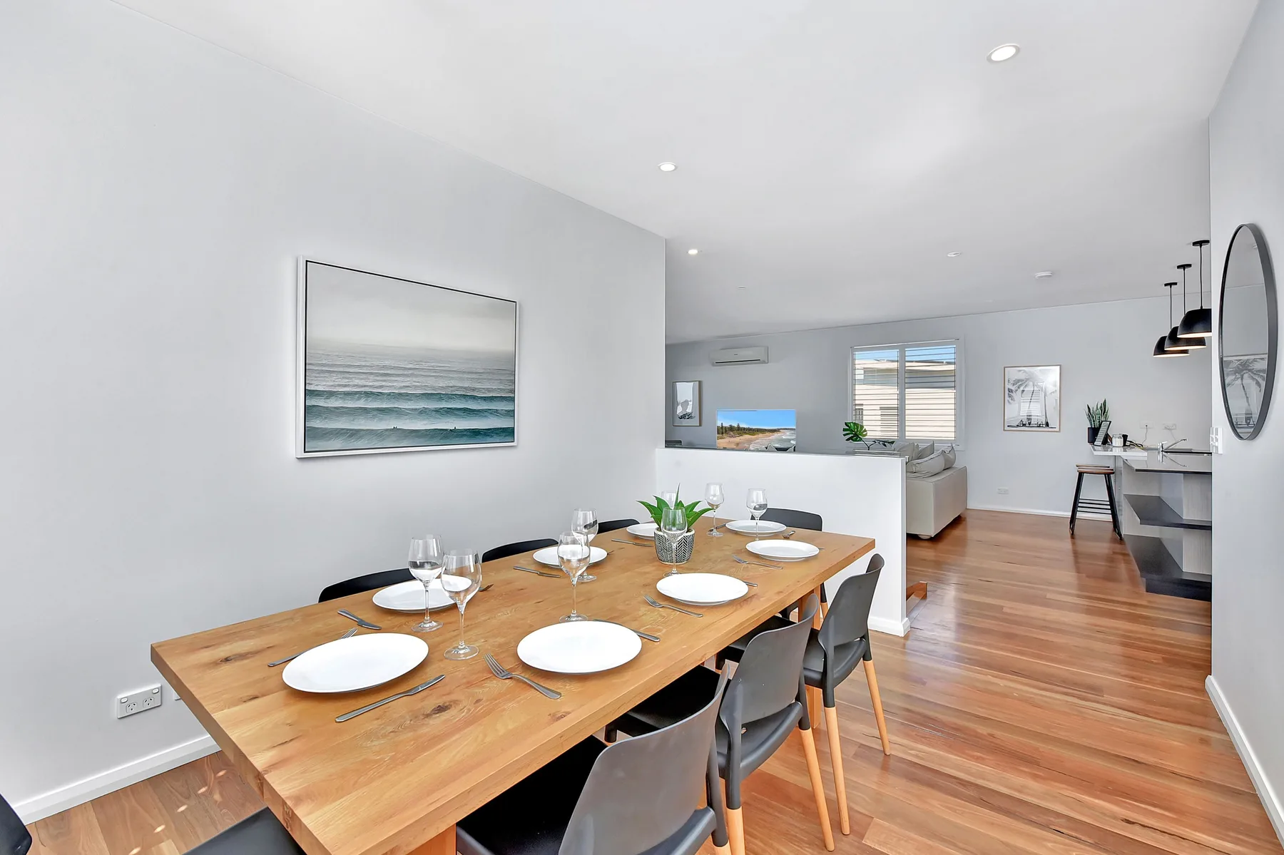 A dining area with a wooden table set beside an open kitchen.