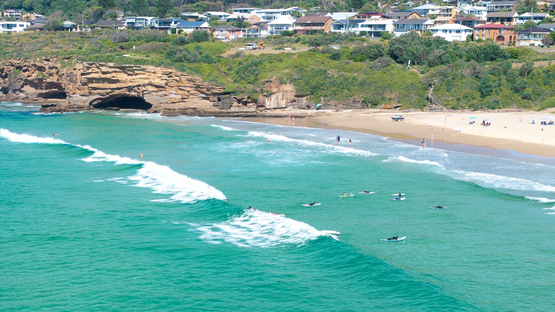 Aerial view of a sandy beach with turquoise water and waves.