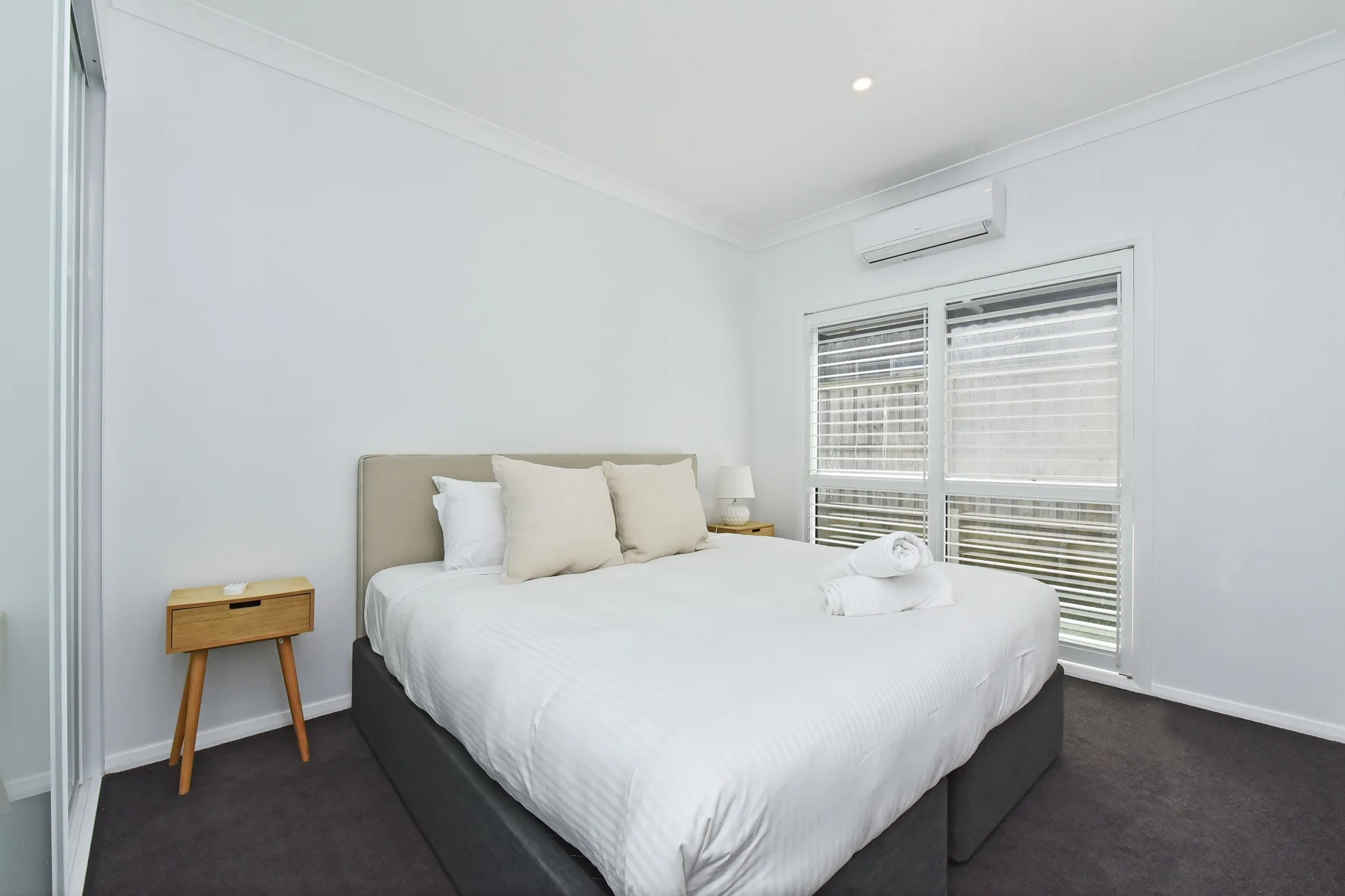 A bright bedroom with a large bed and wide windows.