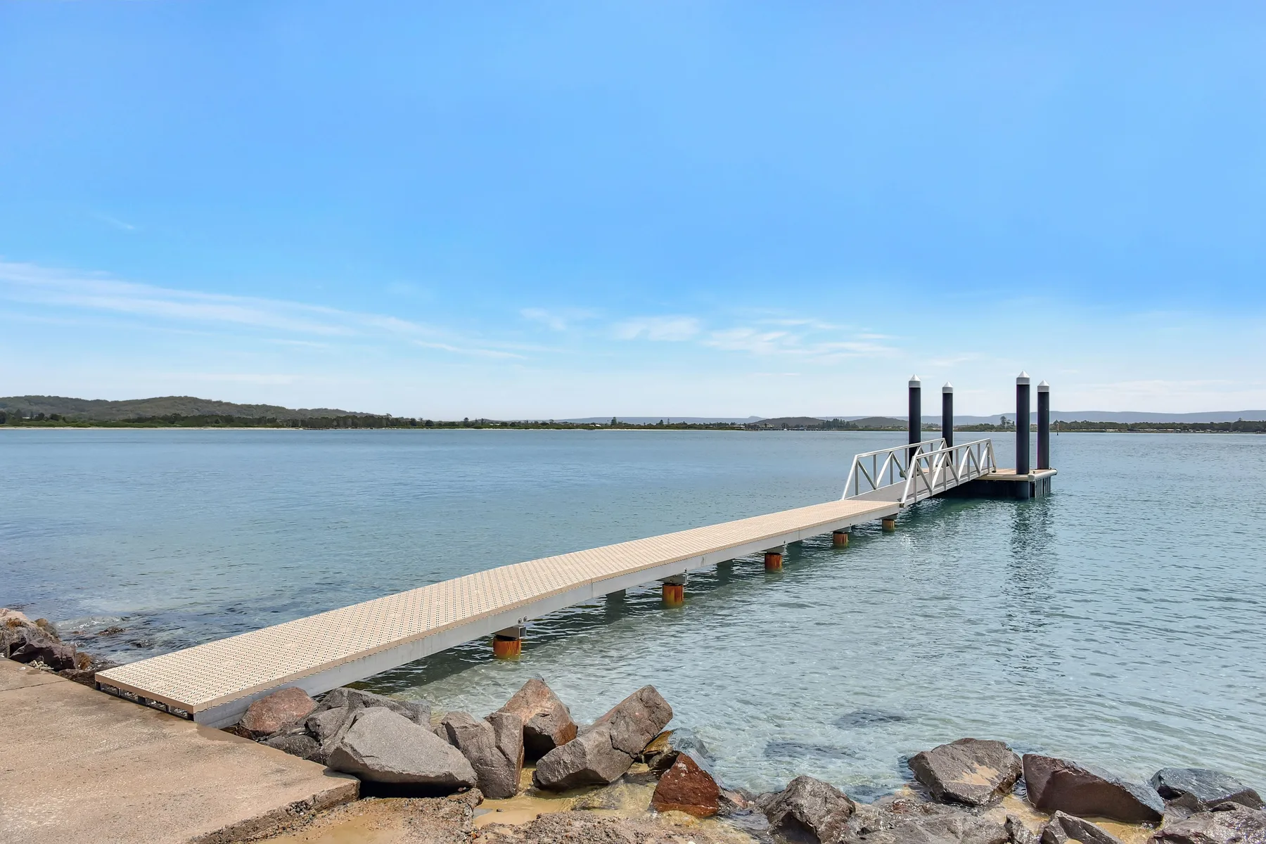 A long dock extends across calm water toward the distant shoreline.
