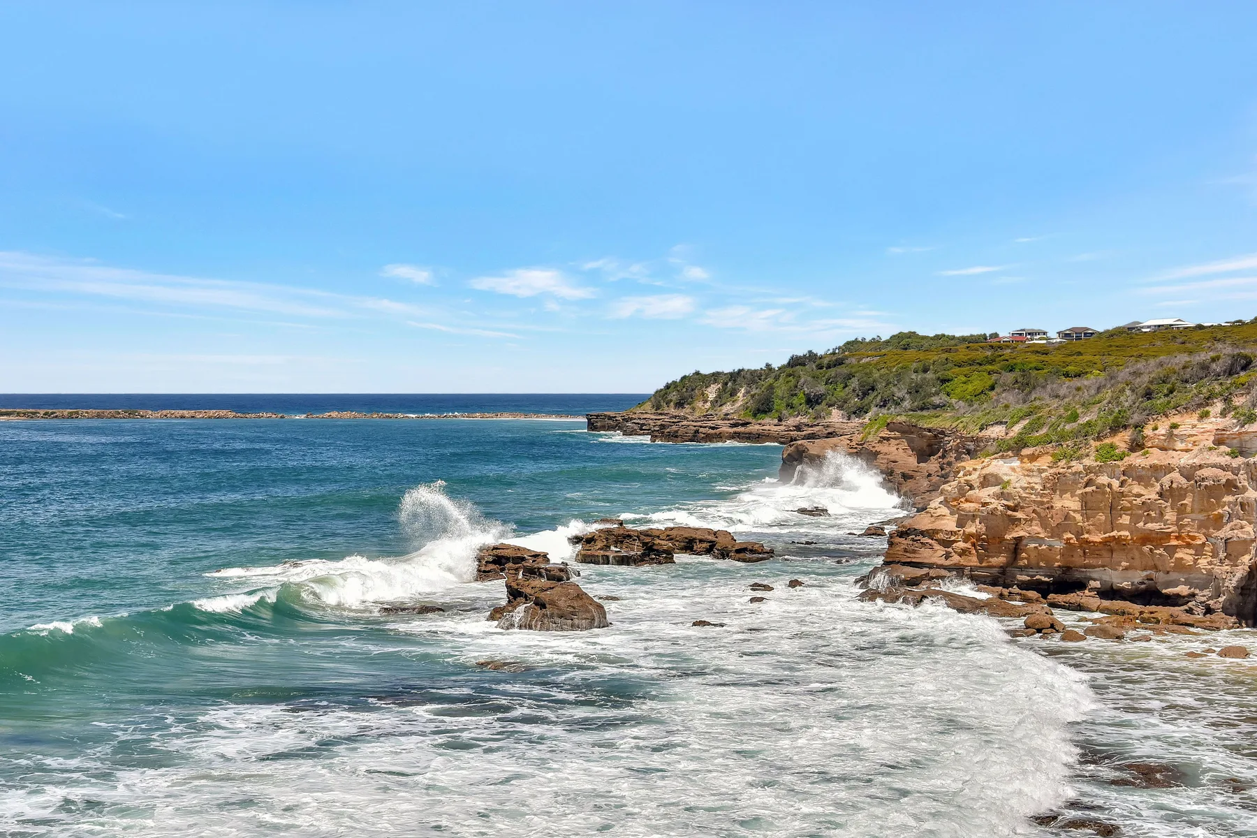 Coastal seascape with waves breaking against rocky cliffs.