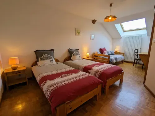 Habitación abuhardillada con dos camas de madera.